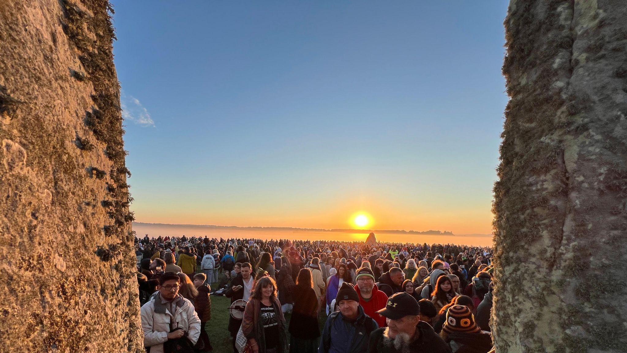 A shot through the stones of the crowd with the sun in the background