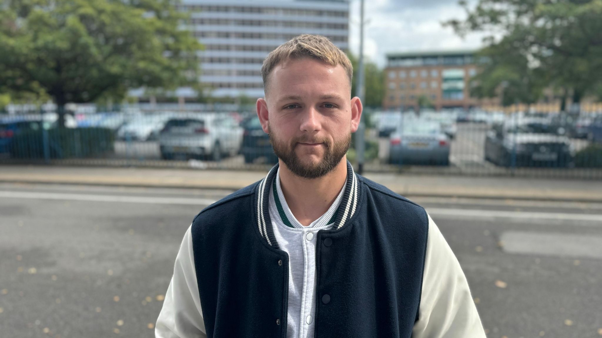 Ipswich Town fan Matt Taber wearing a white and black jacket and grey top standing in front of a car park in Ipswich.