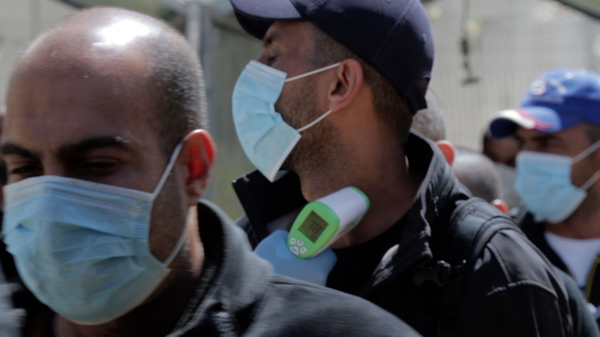 Palestinian medical workers check the temperatures of workers crossing at the Tarqumiya checkpoint, near the West Bank city of Hebron