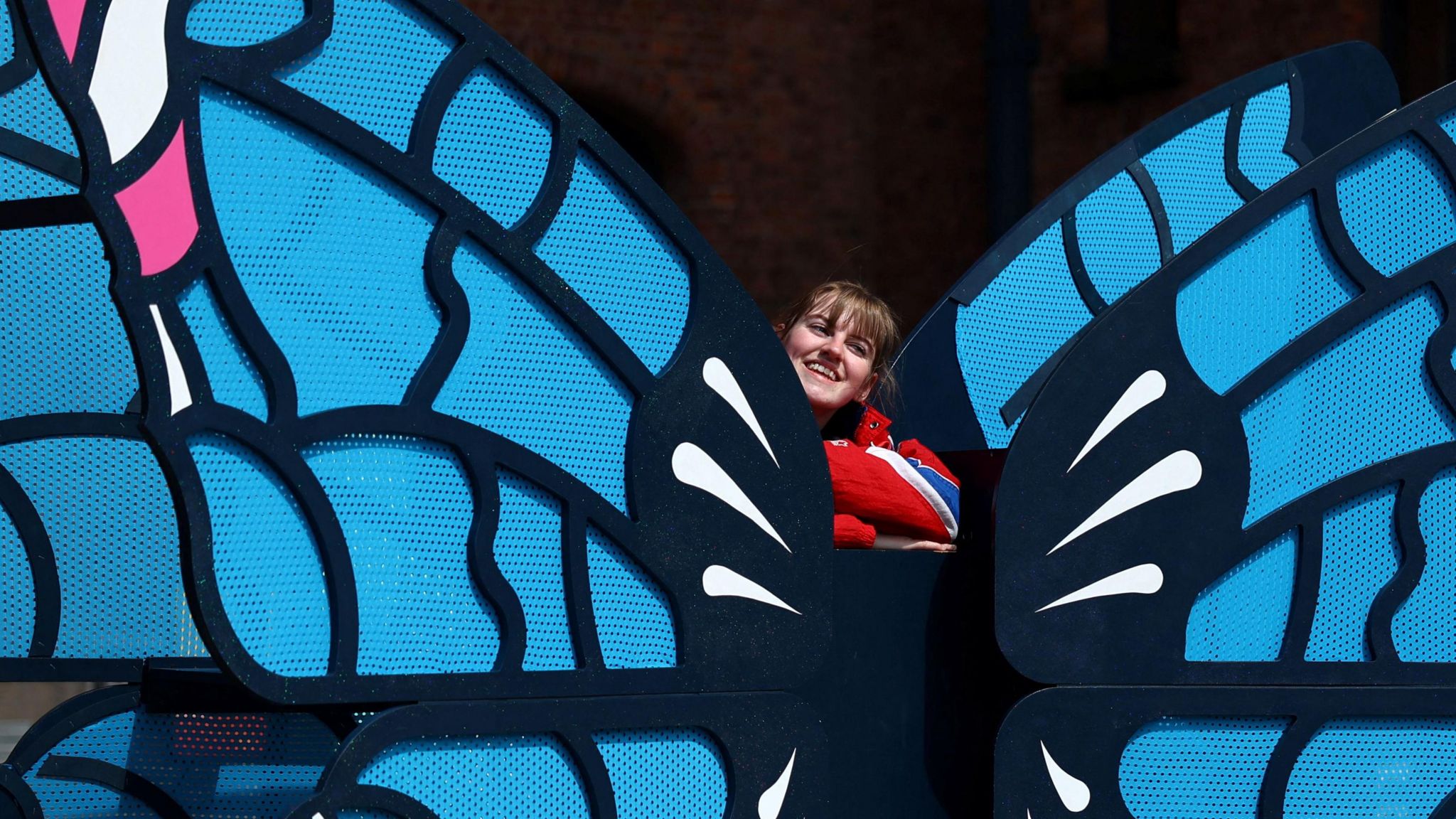 A fan poses next to a butterfly installation on the Taylor Swift trail 