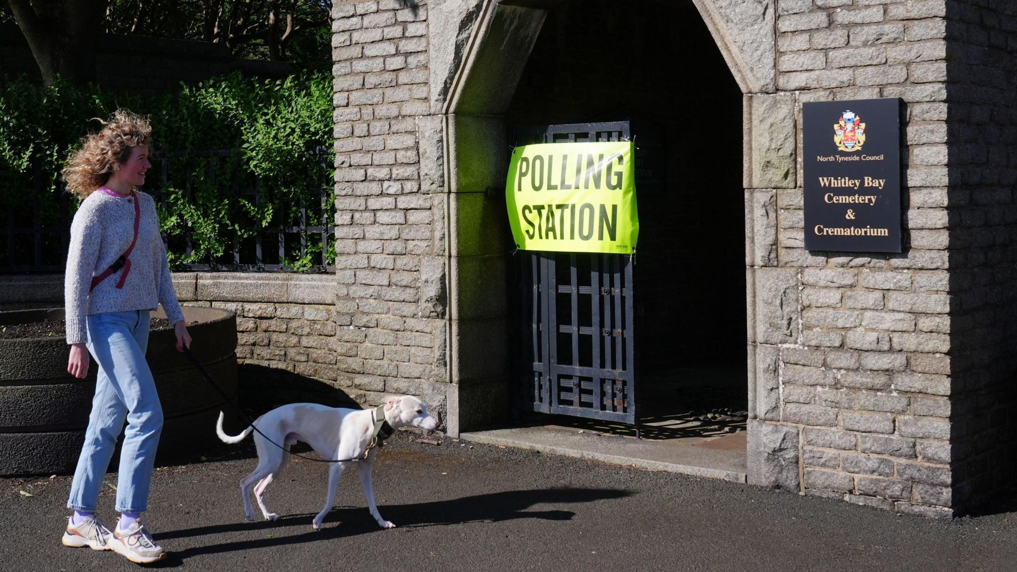 A woman with a dog arrives to cast her ballot at Whitley Bay Cemetery and Crematorium