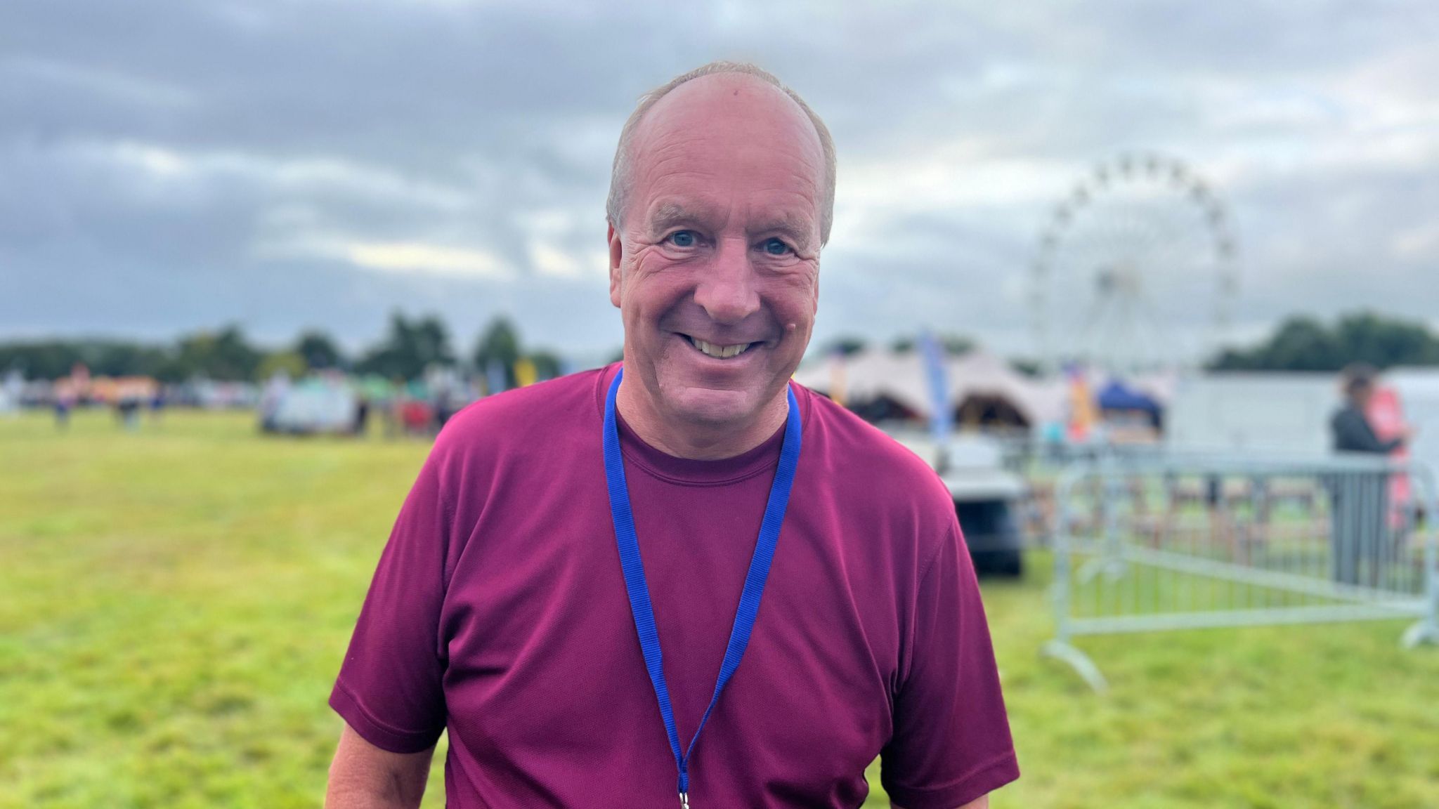 Chris Bailey, pictured in the balloon arena. He wears a maroon t-shirt and a blue lanyard and is smiling at the camera. 