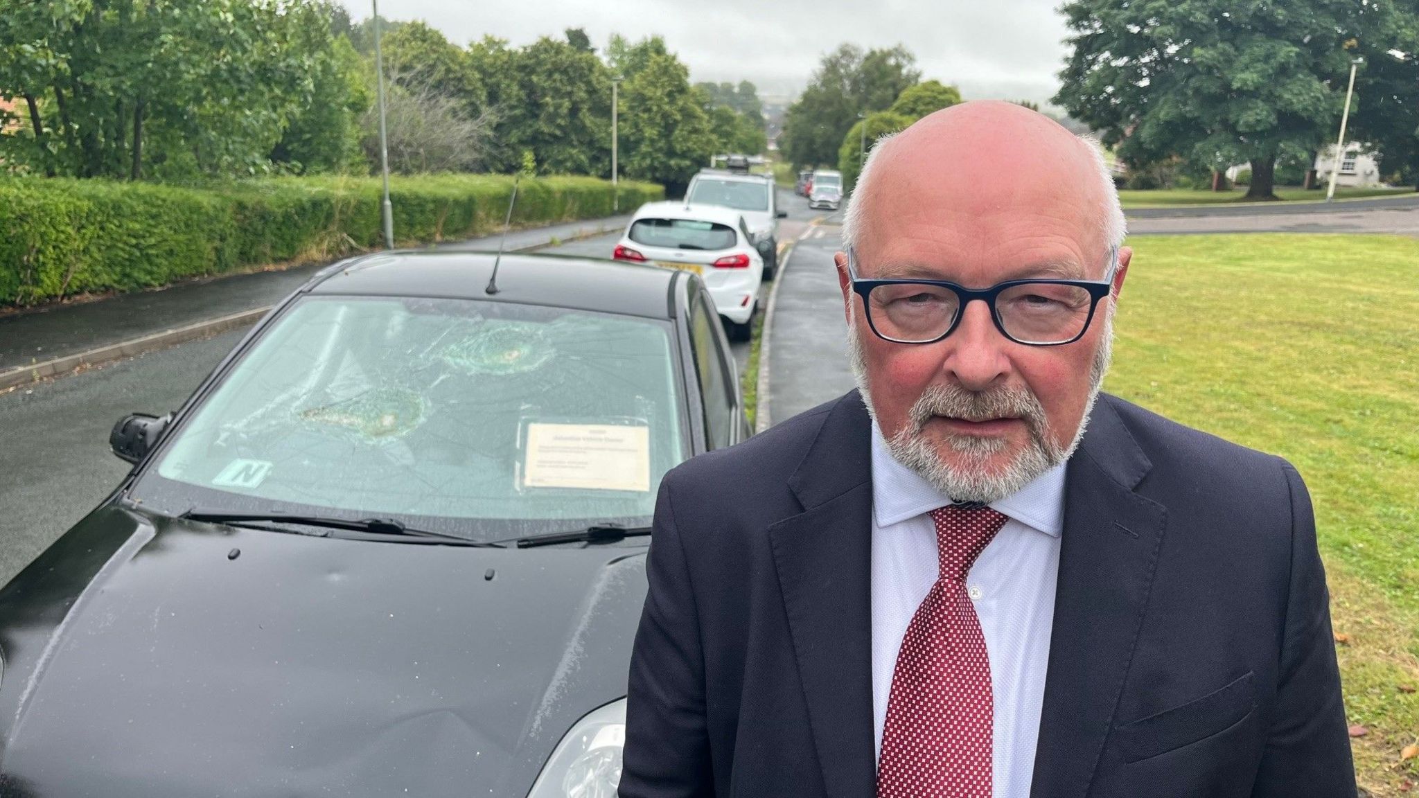 Councillor Alan Connett in front of an abandoned car