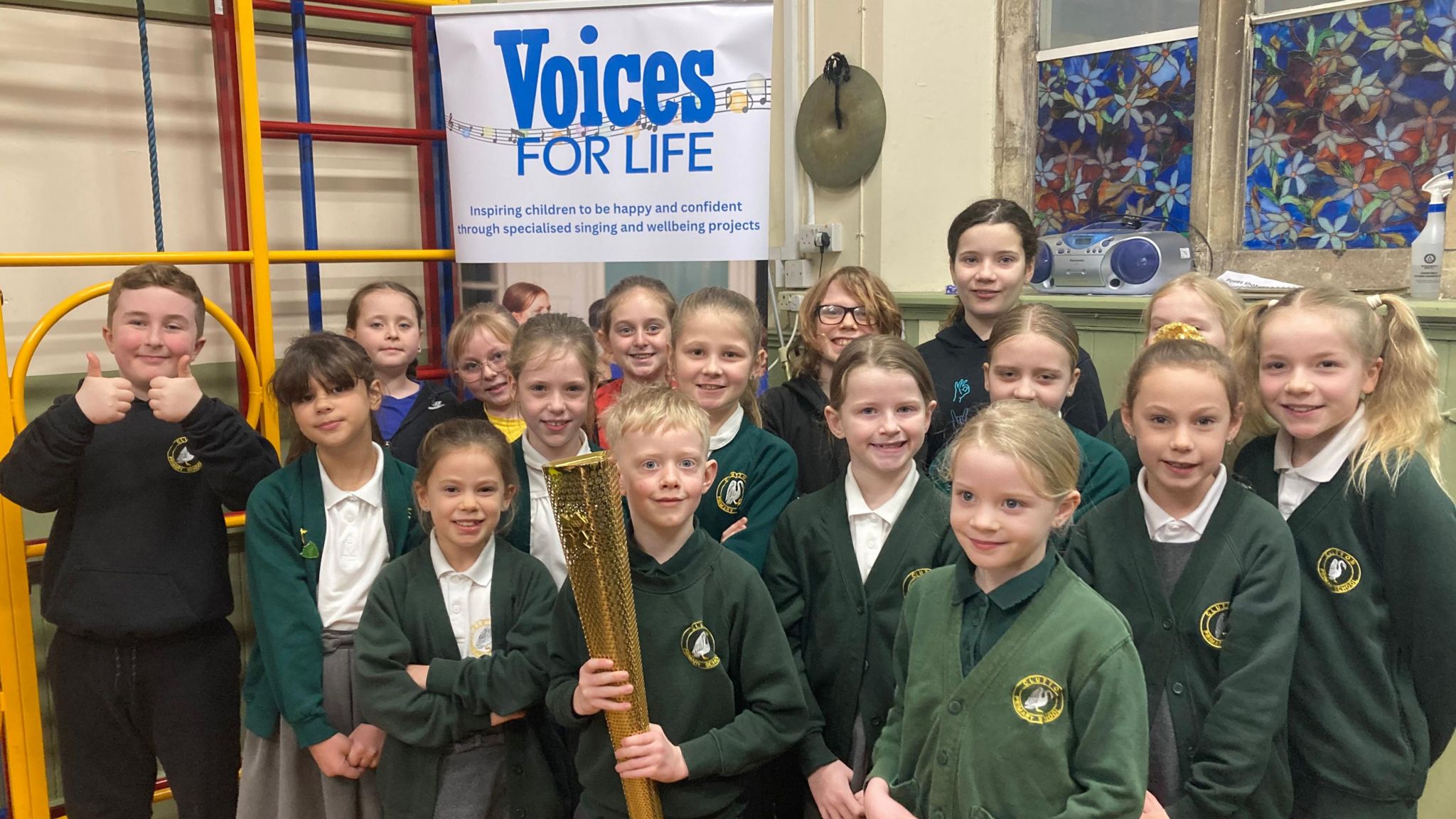 A group of primary school pupils with one holding a London 2012 Olympic torch