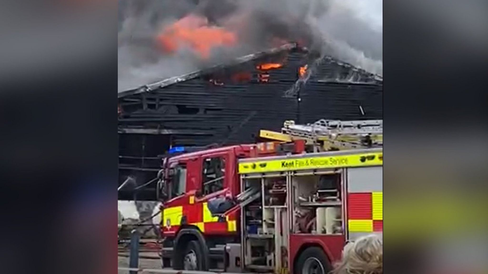 A fire engine dealing with a commercial fire in a black wooden building