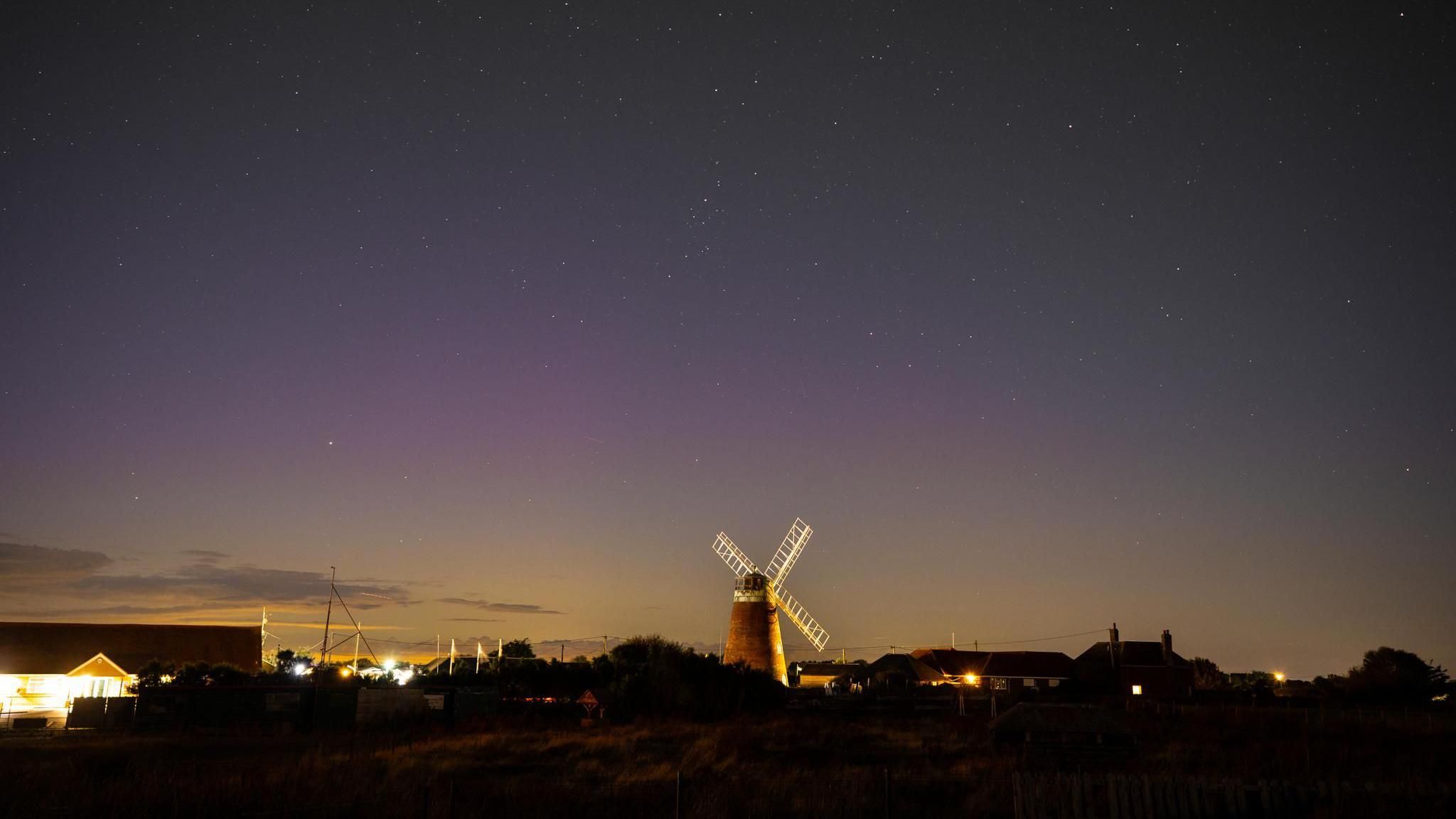 The sky with a pink tinge with a windmill in the foreground