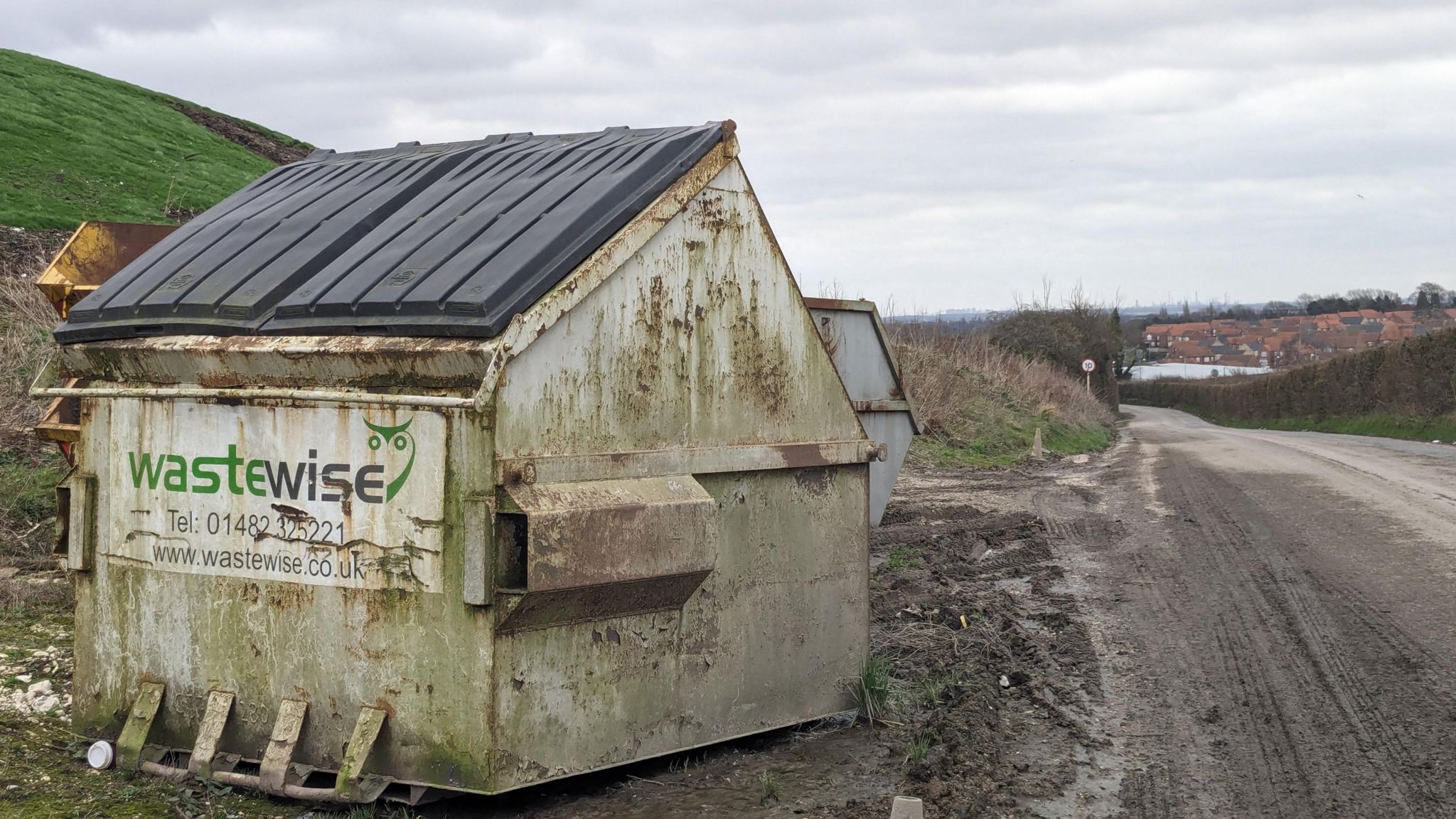A skip with houses in the distance.