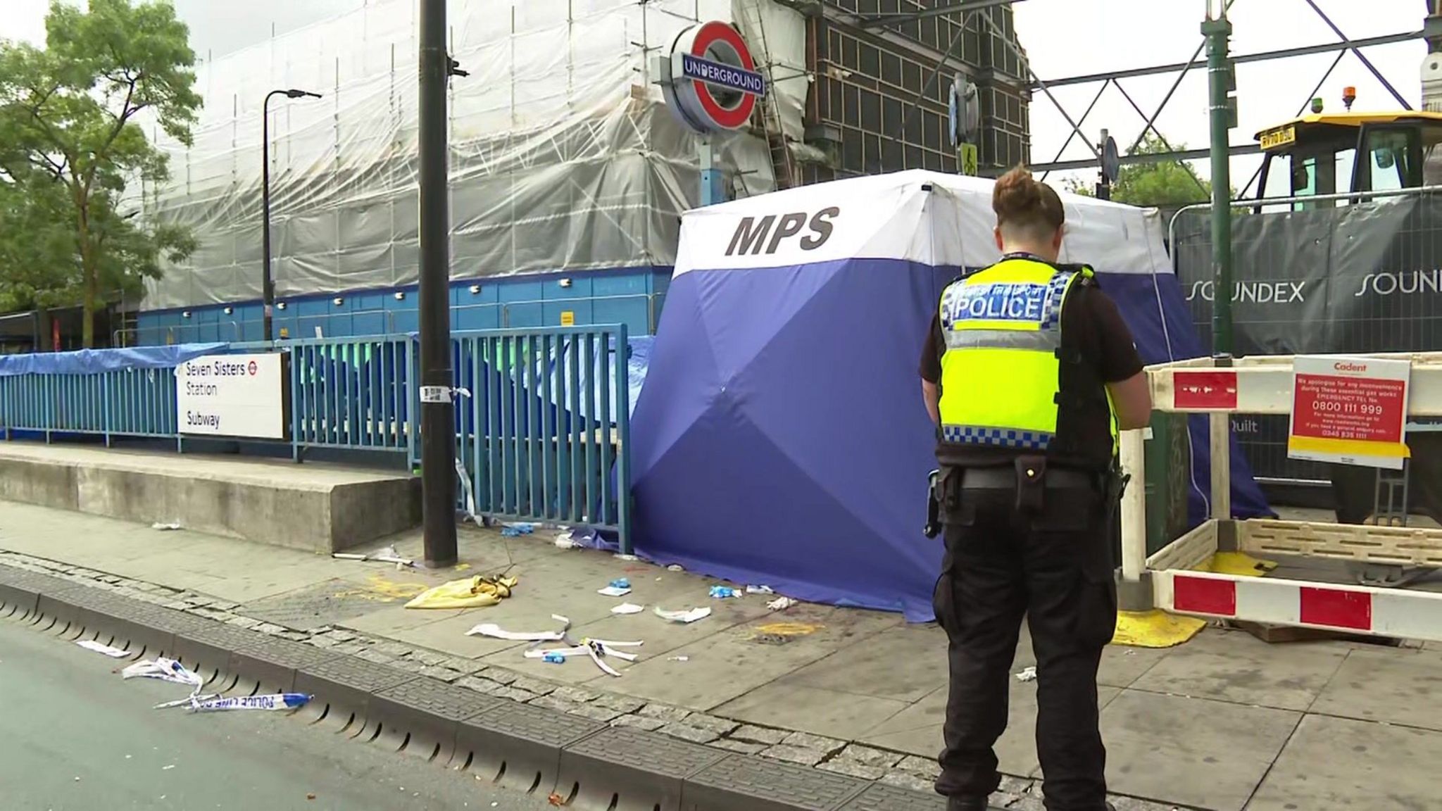 A police officer stands in front of an entrance to Seven Sisters station, with discarded medical wrappers, a forensic tent and tarpaulin