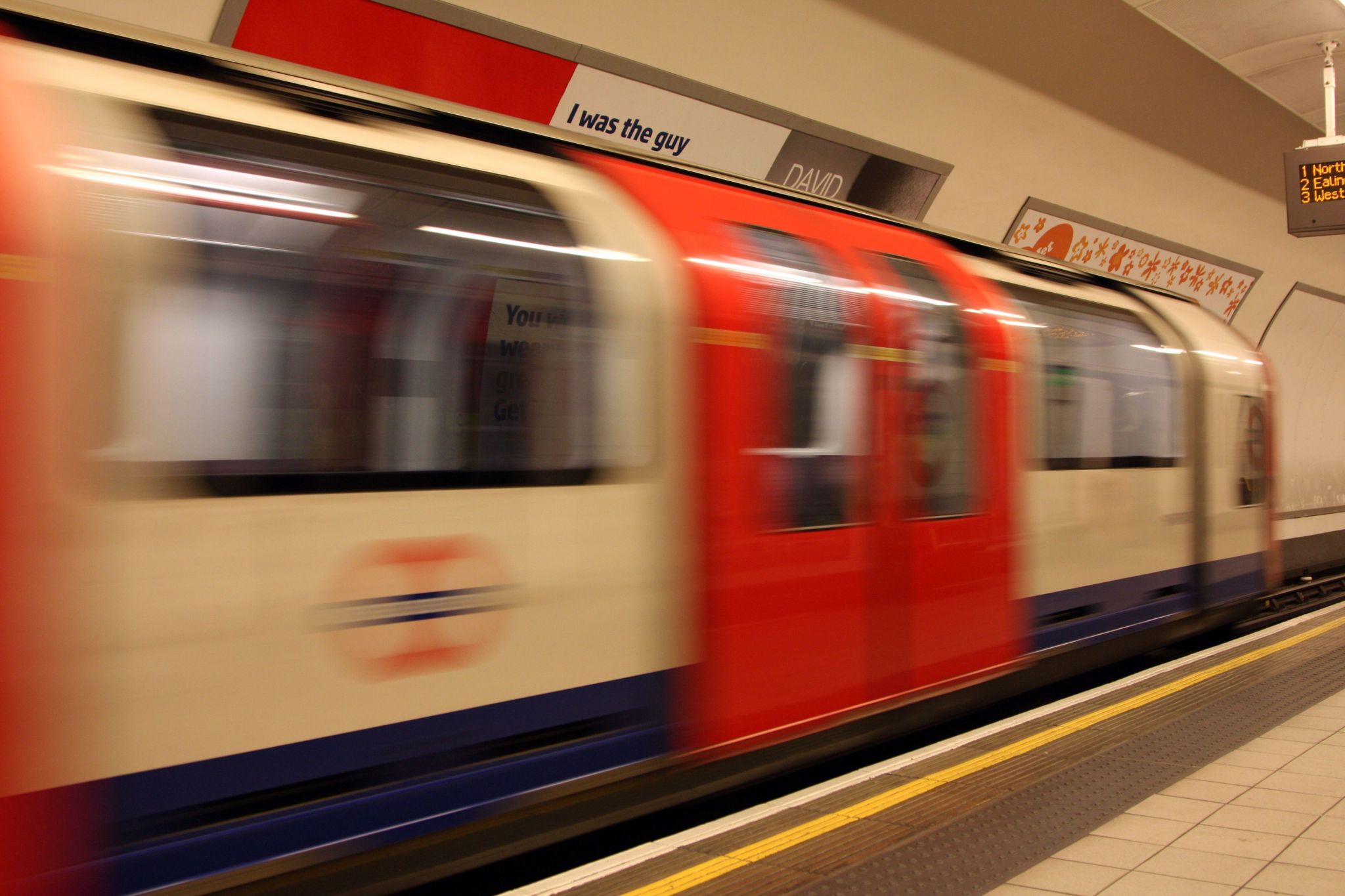 Central Line tube train pulling in next to platform at Shepherds Bush station in 2022