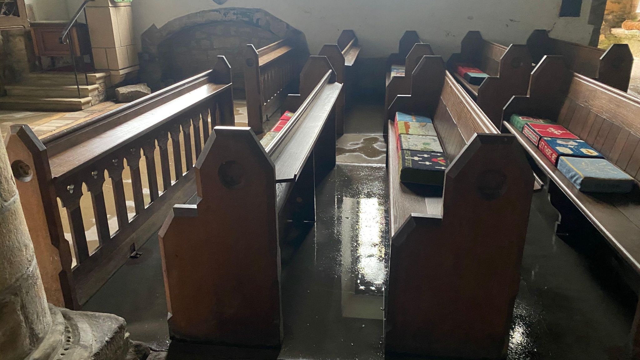 Rows of pews with water on the floor