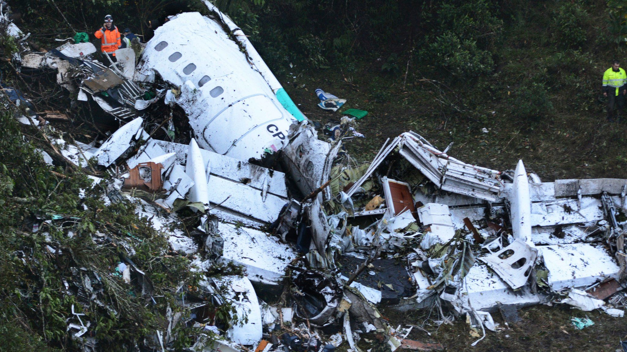 Rescue workers stand at the wreckage site of a chartered airplane that crashed in a mountainous area outside Medellin, Colombia