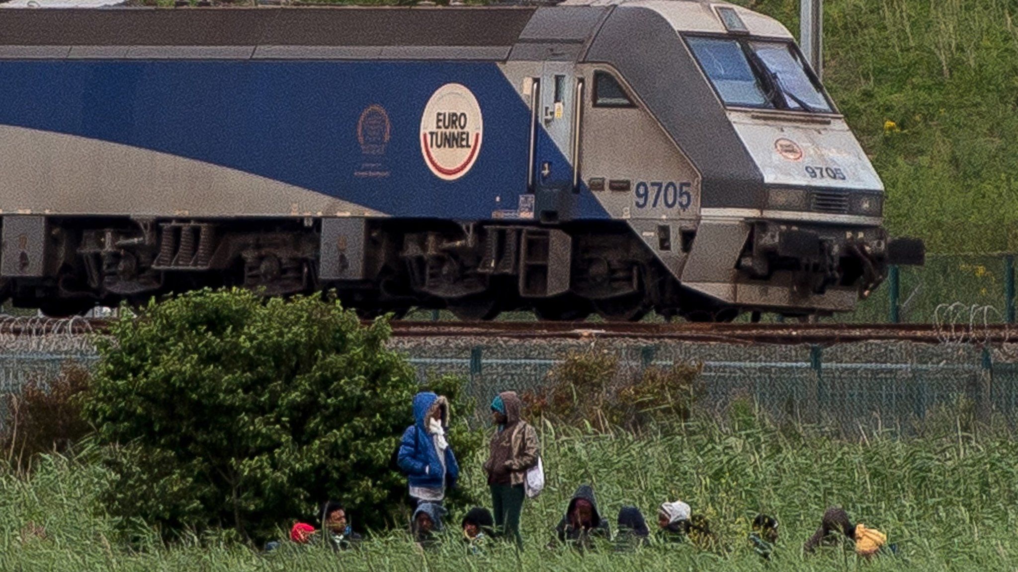 Migrants wait near Eurotunnel tracks in Calais on 29 July 2015