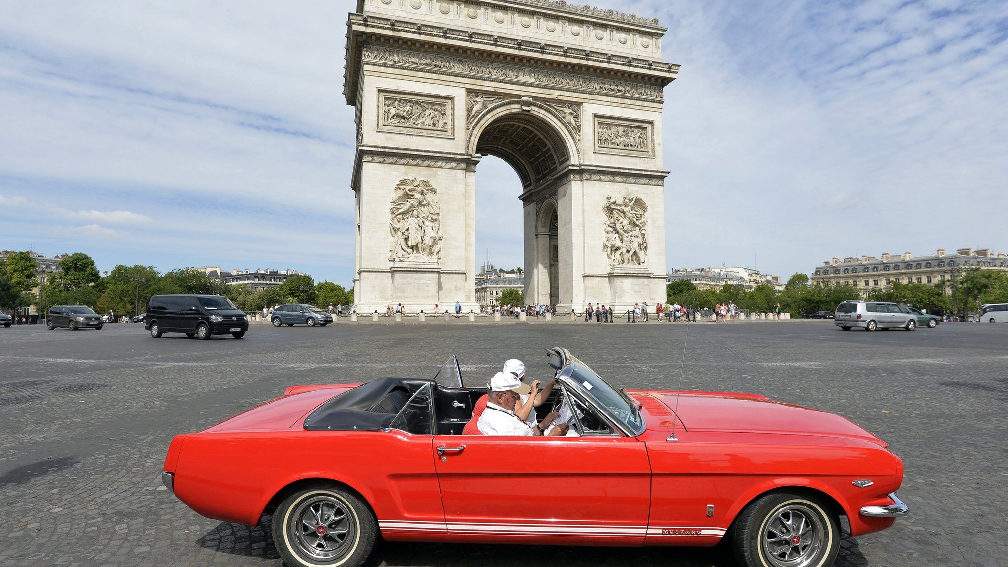 A convertable car in front of the Arc de Triomphe