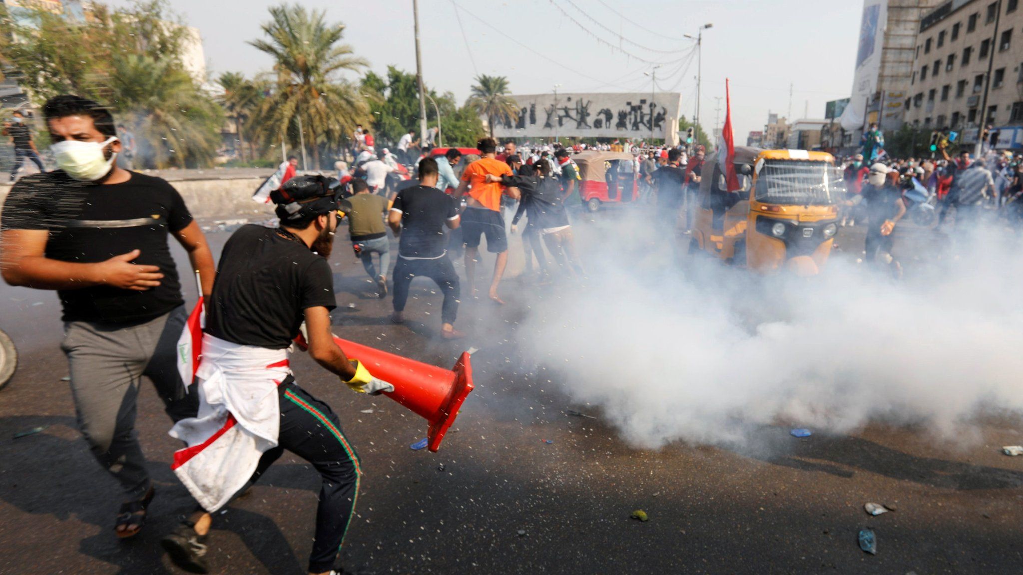 Anti-government protesters run from a tear-gas canister during a protest in Tahrir Square, Baghdad (28 October 2019)