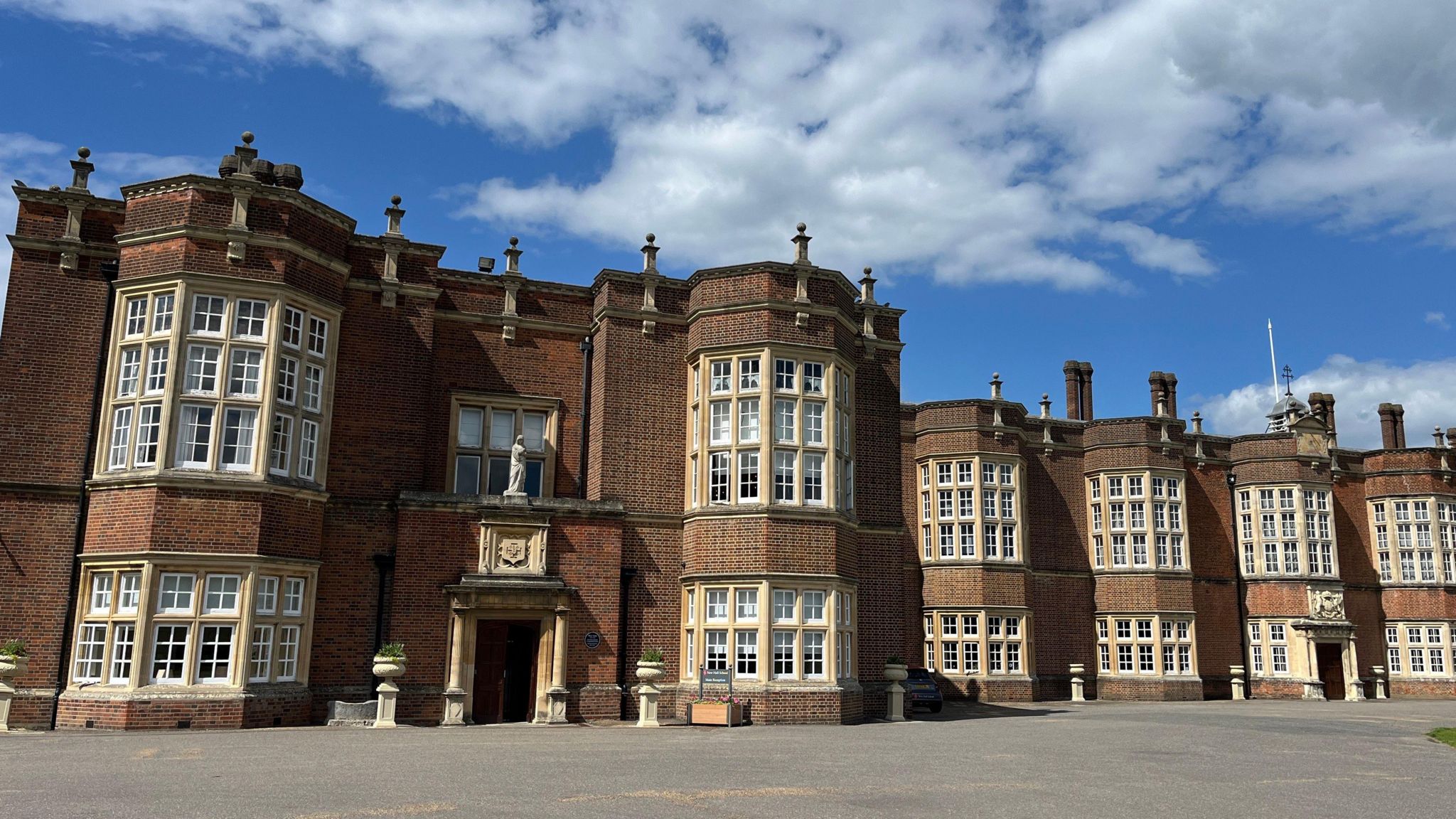 Exterior view of New Hall school, an impressive red brick building with a series of stone bay windows