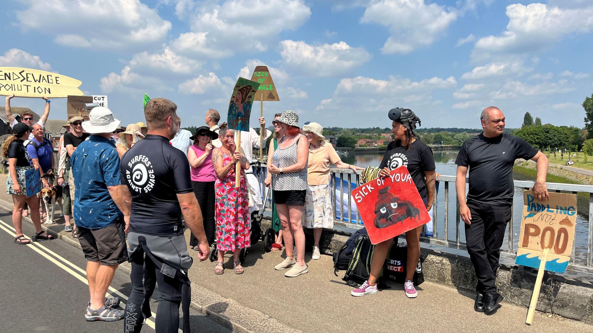 Campaigners with messages on card that say things like "sick of your poo" and they are stood on a bridge over the river itchen for the protest