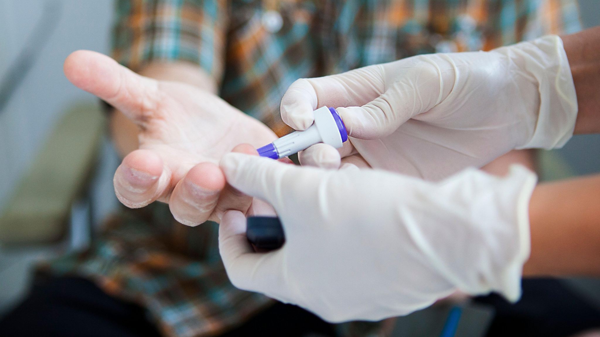 Image of a doctor performing a finger prick test on a patient