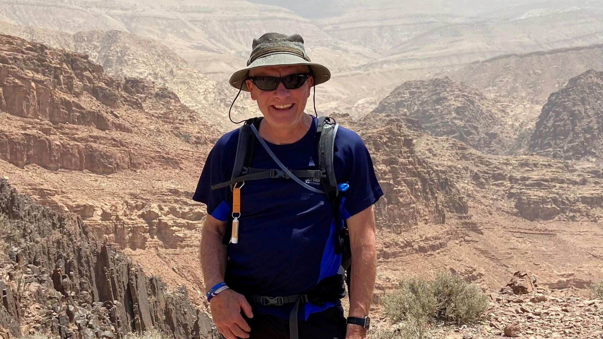 Colin Ford on a previous trek standing in a desert area wearing a hat and sunglasses