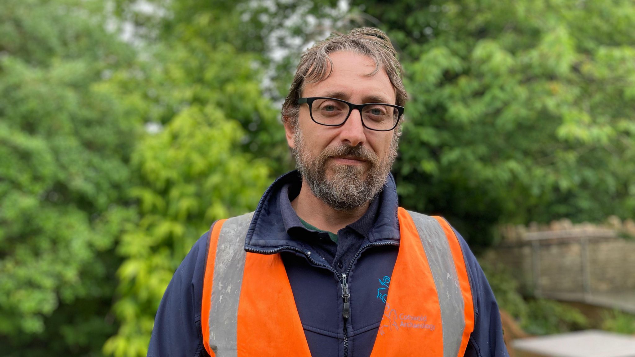Paulo Guarino wearing glasses and high-vis vest looks into the camera