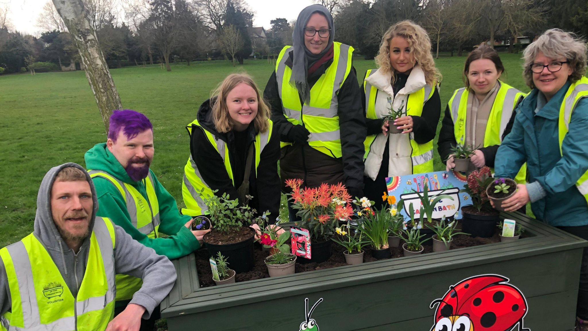 Volunteers, in high-vis jackets, standing around one of the planters