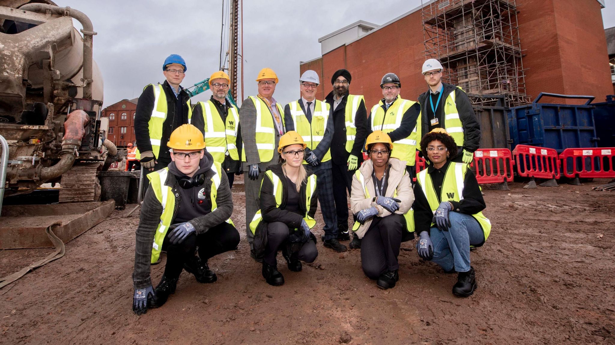 A group of people in hi-vis vests and hard hats on the building site for the City Learning Quarter city centre development