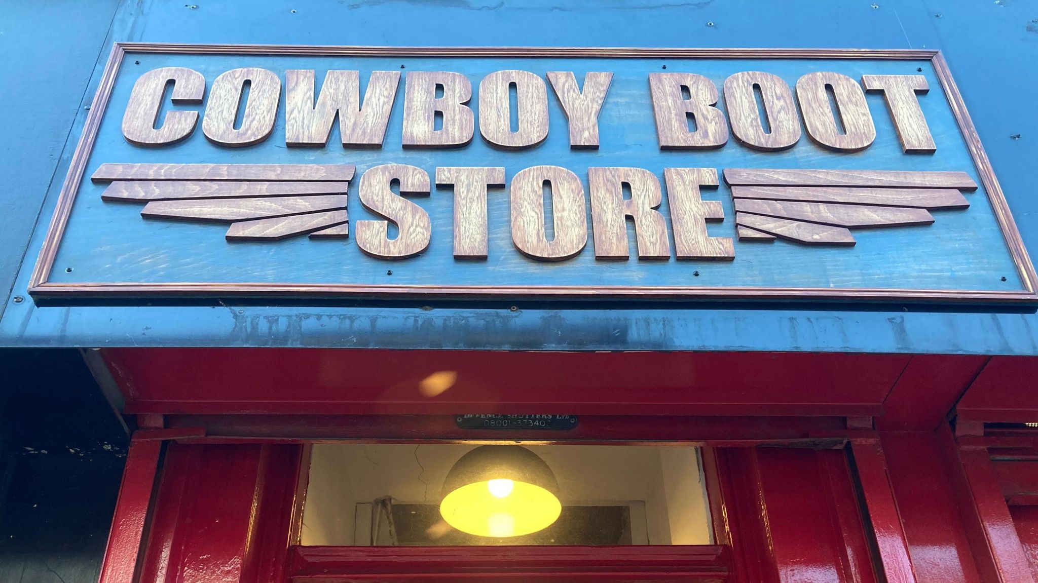 Blue shop sign displaying the words Cowboy Boot Store