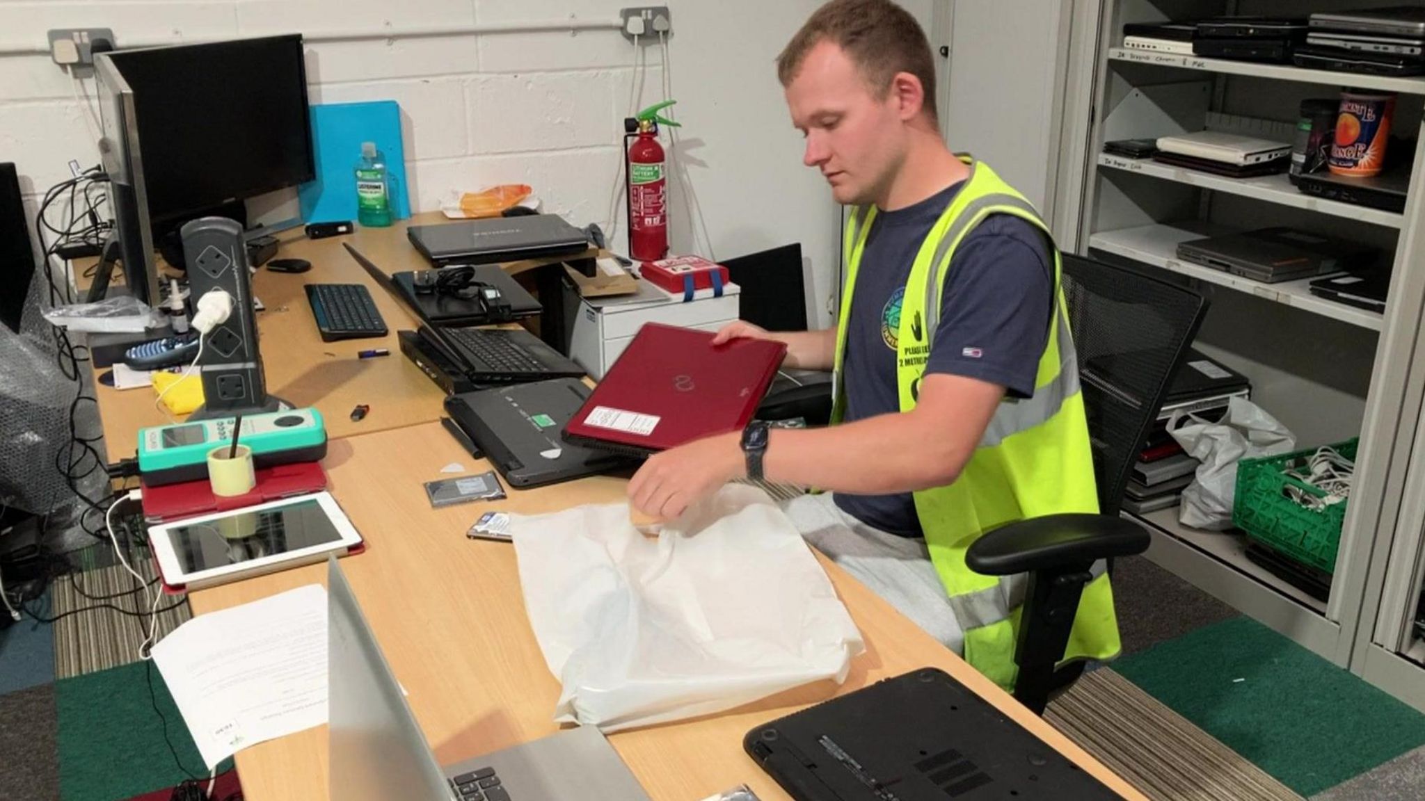 Man in high vis vest putting laptop in a parcel bag
