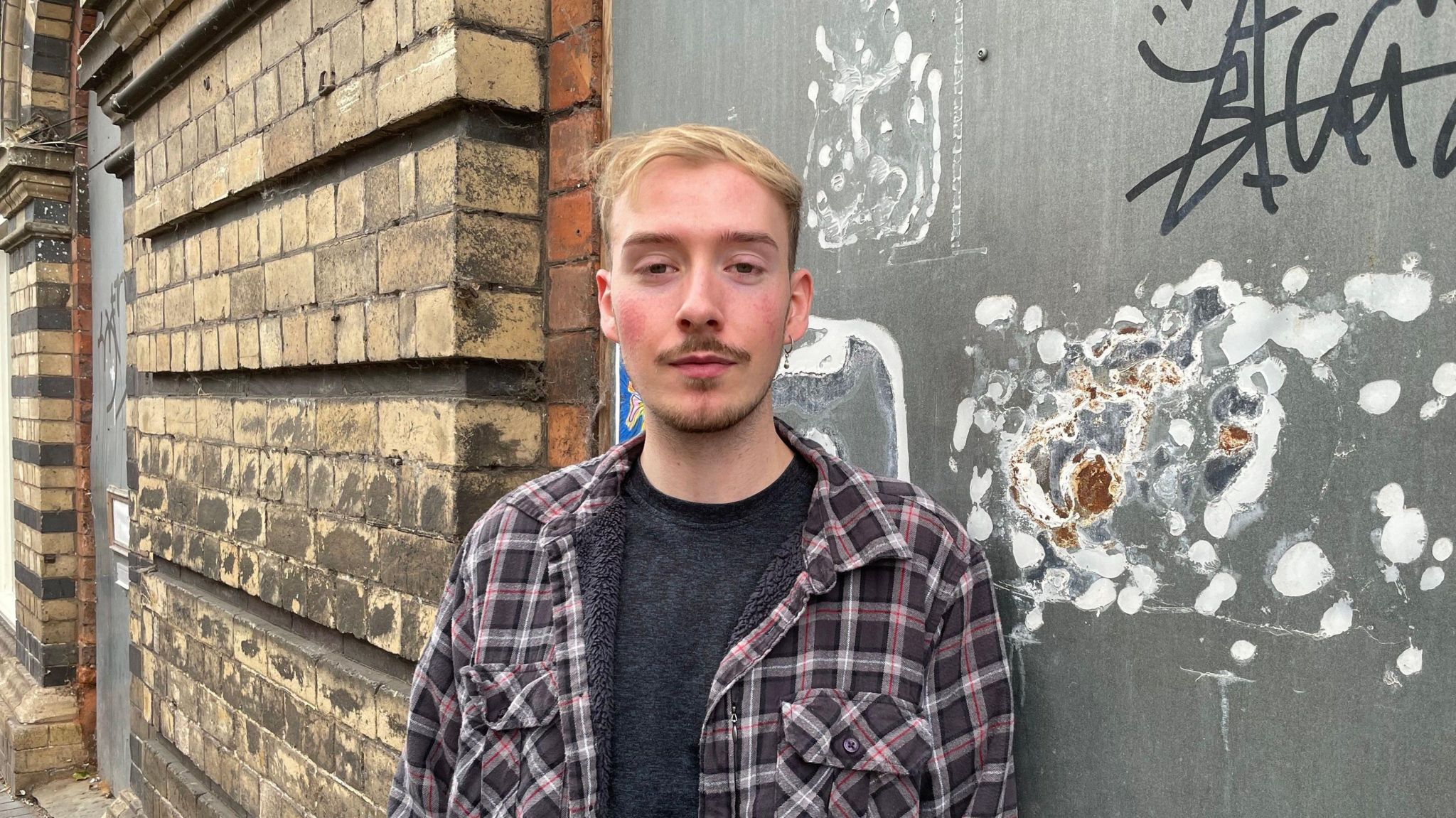 Bridgnorth resident and petitioner Huw Rees looking unhappy in front of the New Market Hall, which has crumbling brickwork and graffiti on a boarded up doorway 