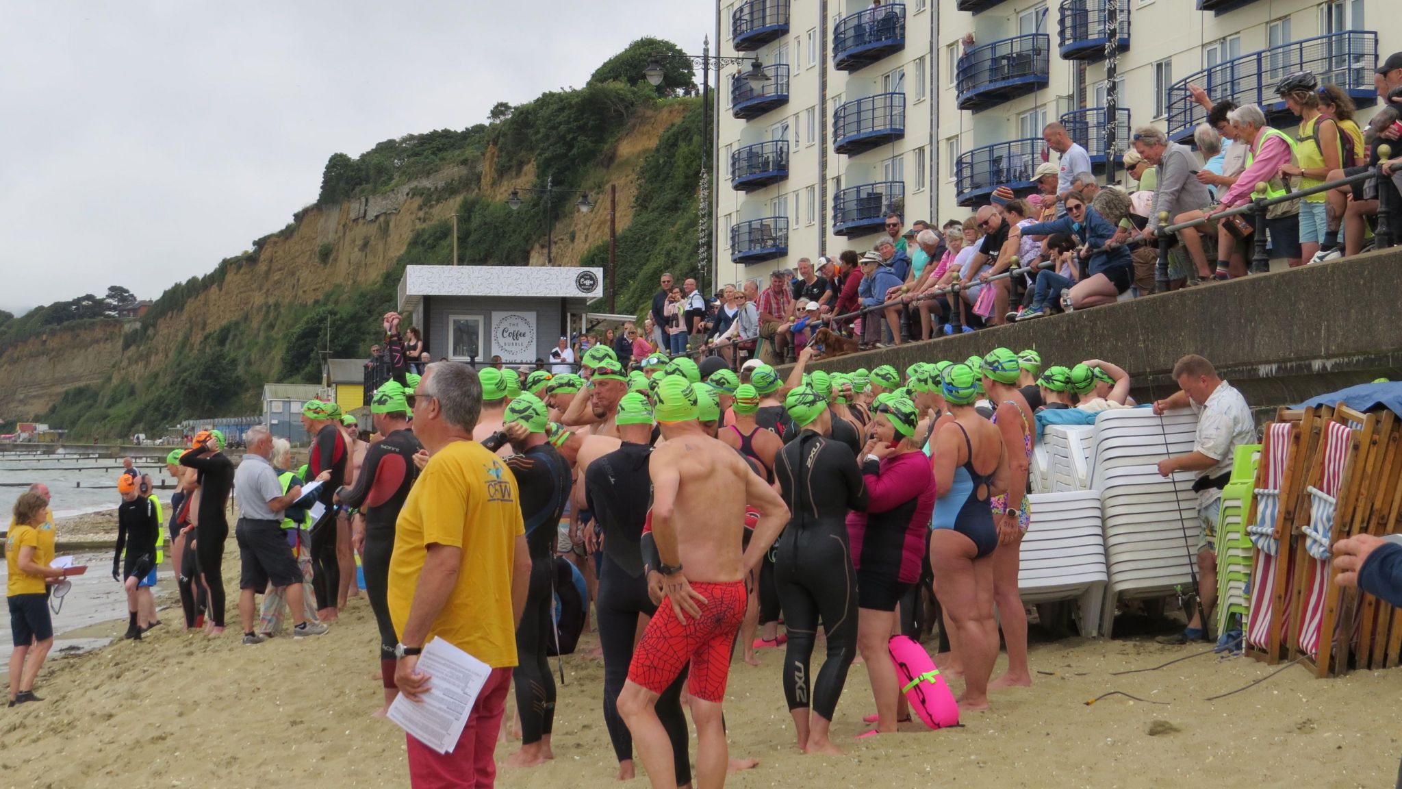 Swimmers stood on the beach wearing pink swimming caps