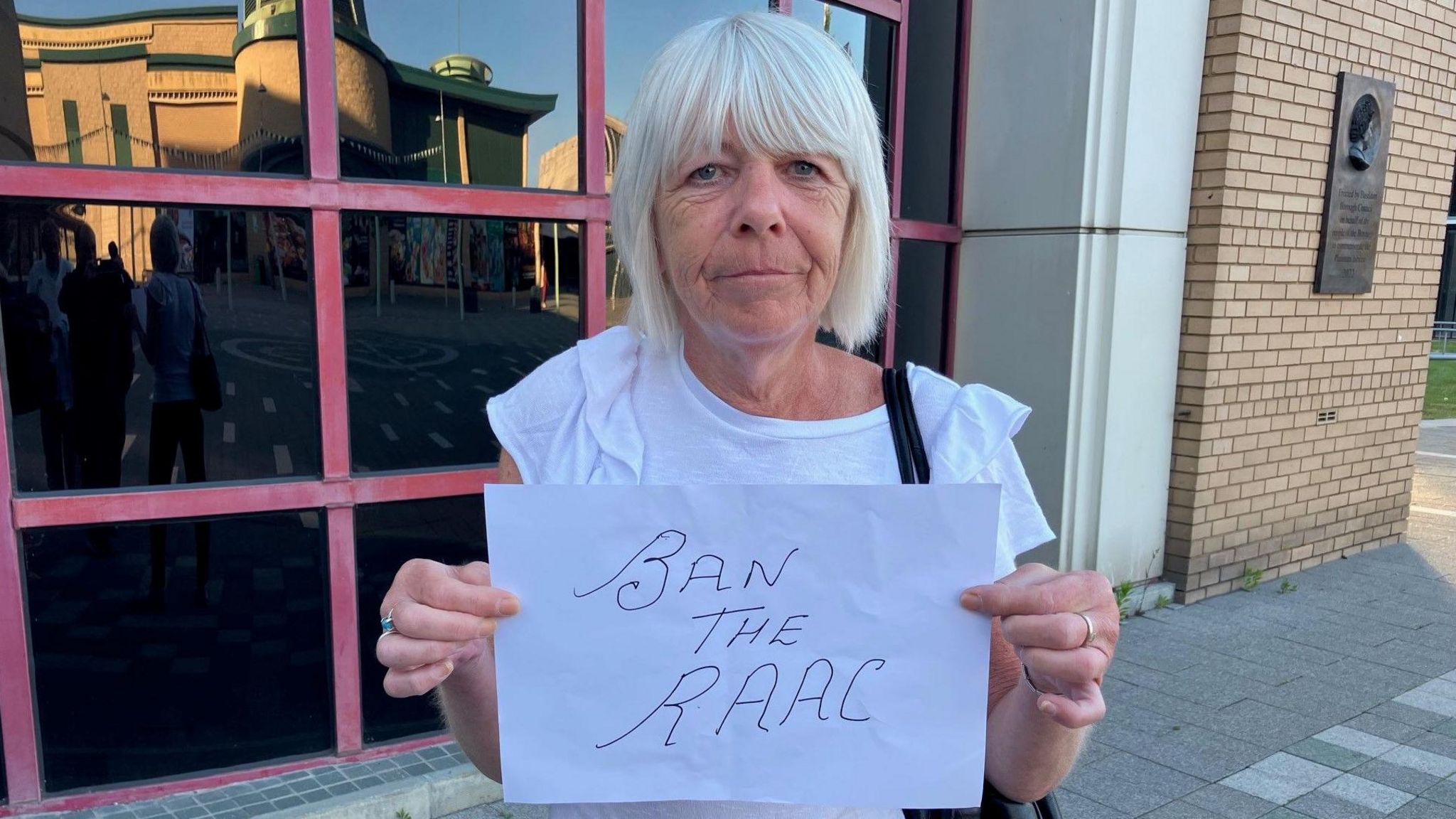 A lady called Sharon Tillbrook holding a 'Ban the Raac' sign outside the Basildon Centre