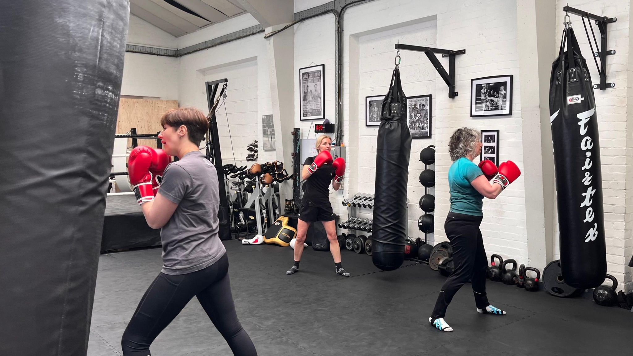 Three women training boxing skills on punching bags