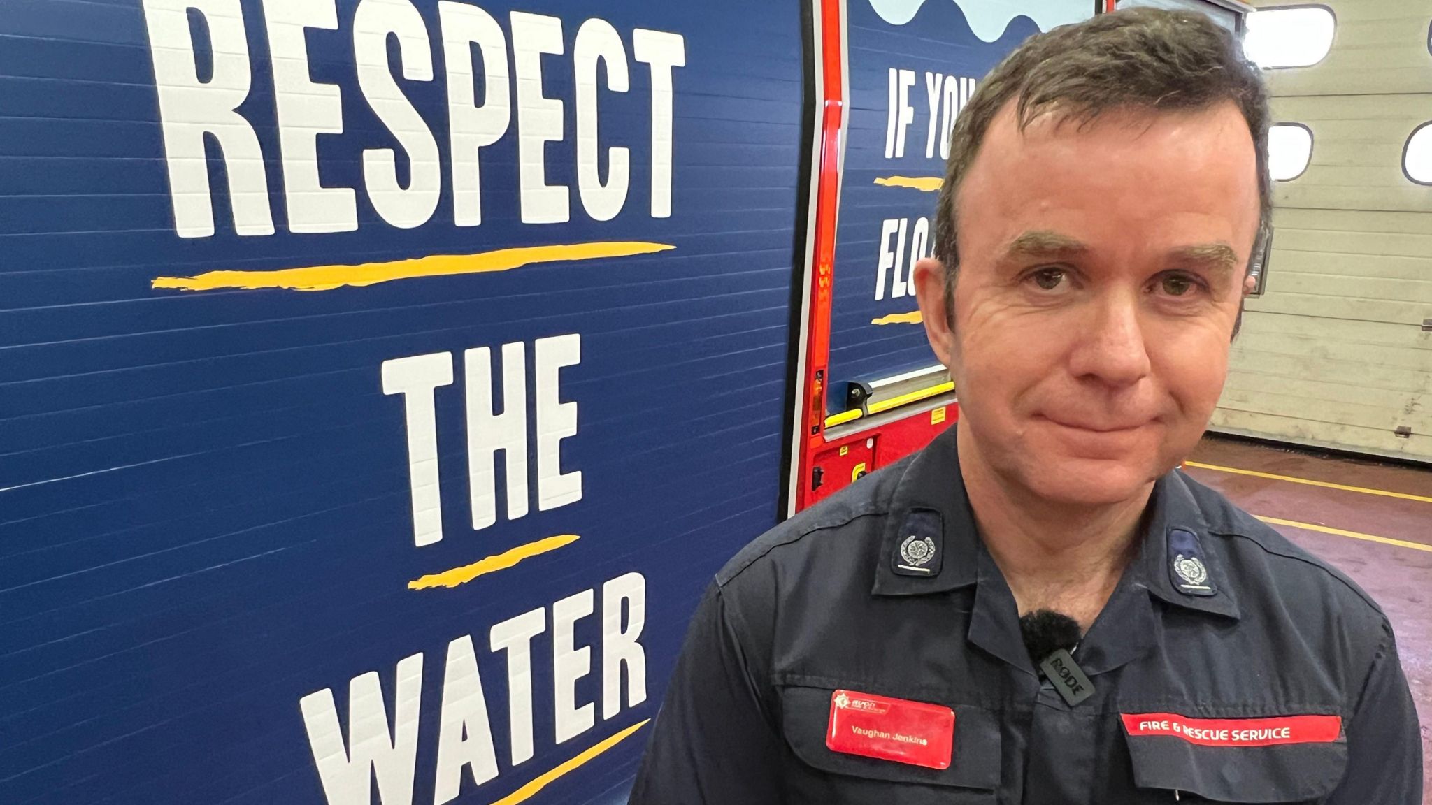 A man stands in front of a fire engine