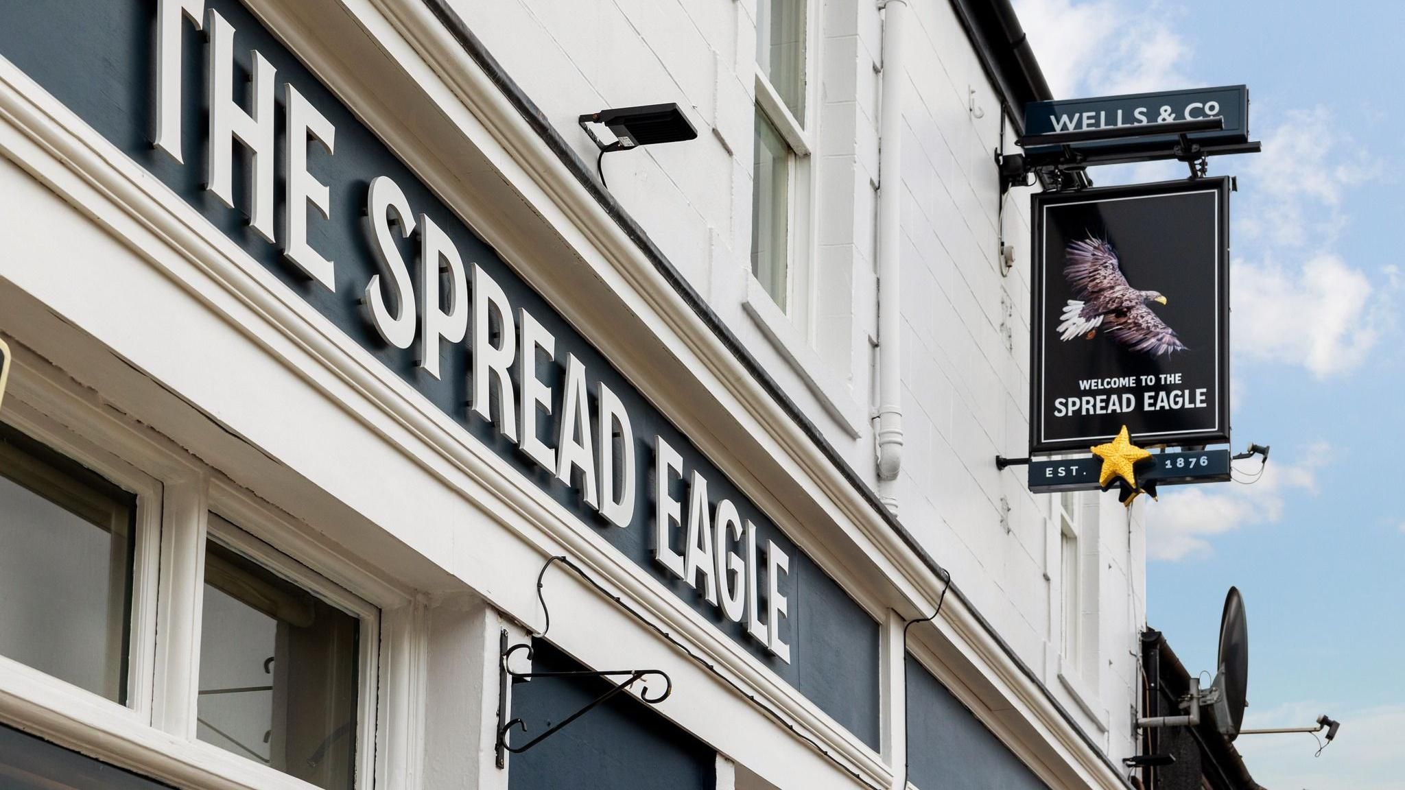 The outside of the pub with a sign with an eagle on