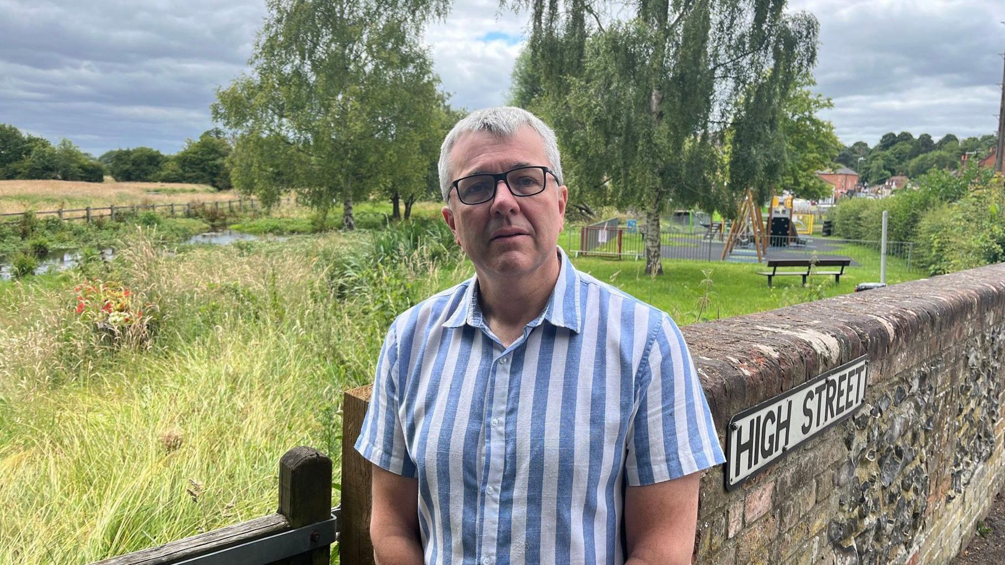 Robert Gill, in a stripy short-sleeved shirt, looking concerned as he stands close to the River Misbourne