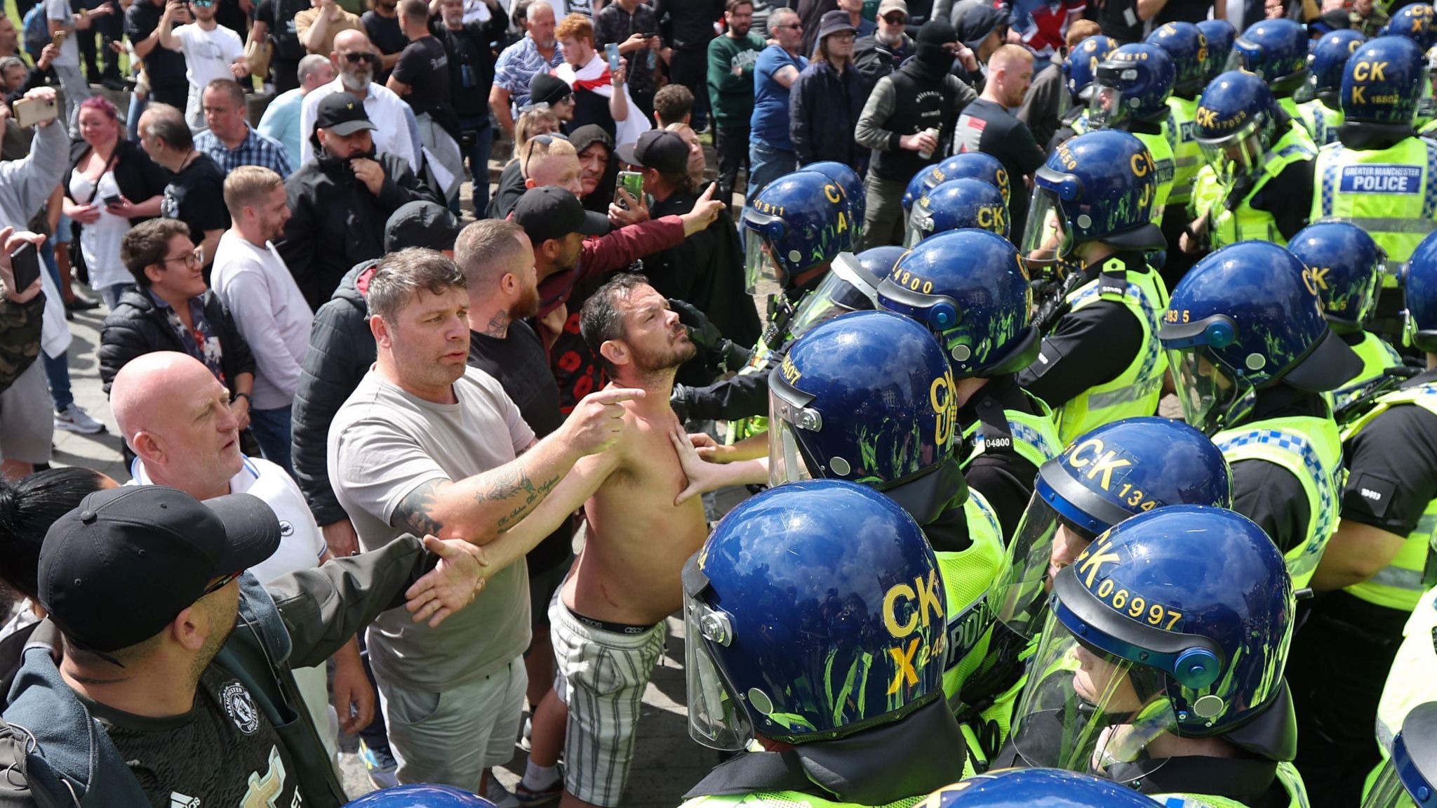 Protesters face a line of riot police in Manchester