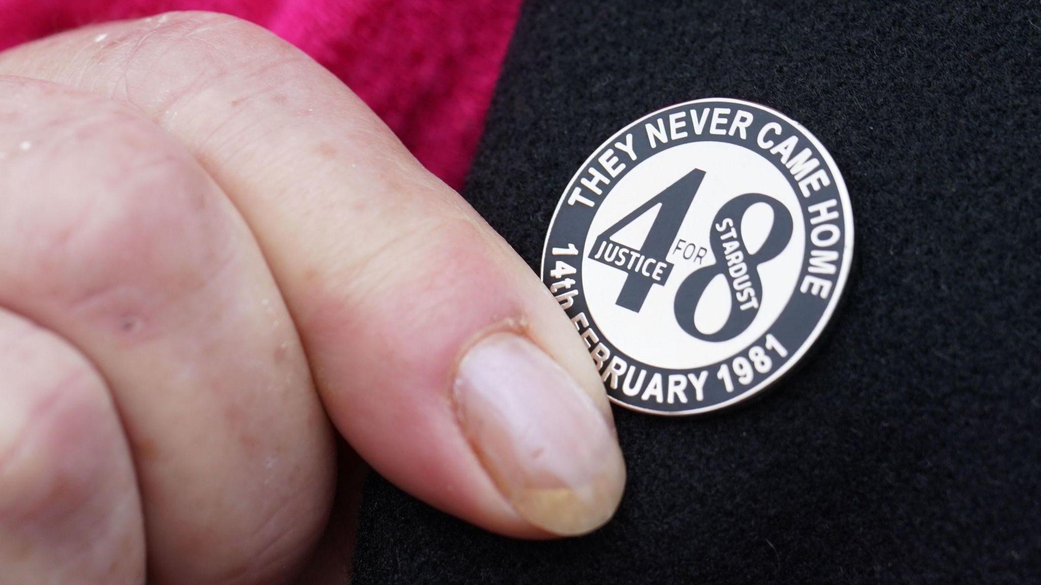 Woman touching badge saying 48 they never came home
