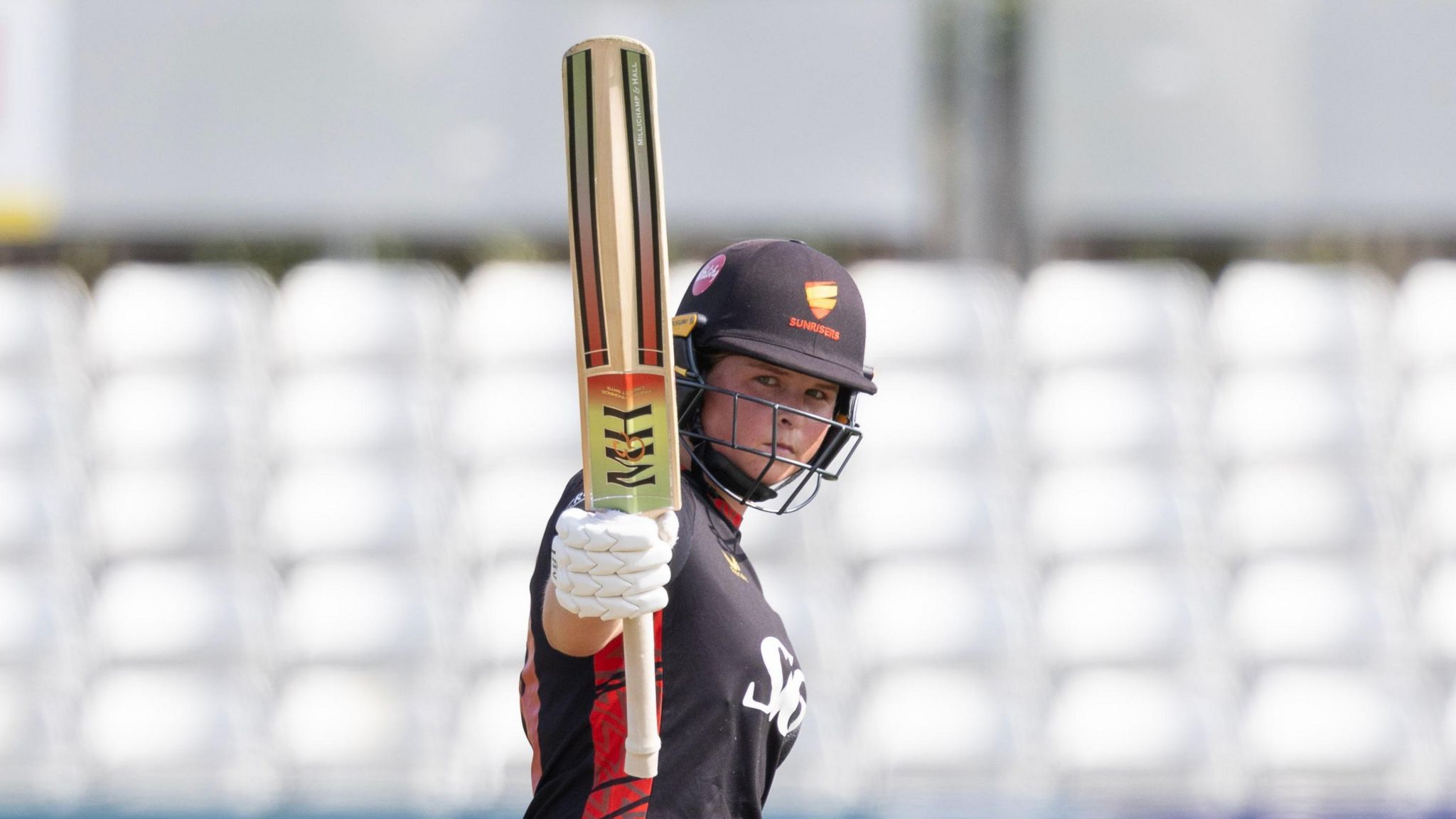 Sunrisers' Grace Scrivens raising her bat upon reaching 50 against Northern Diamonds