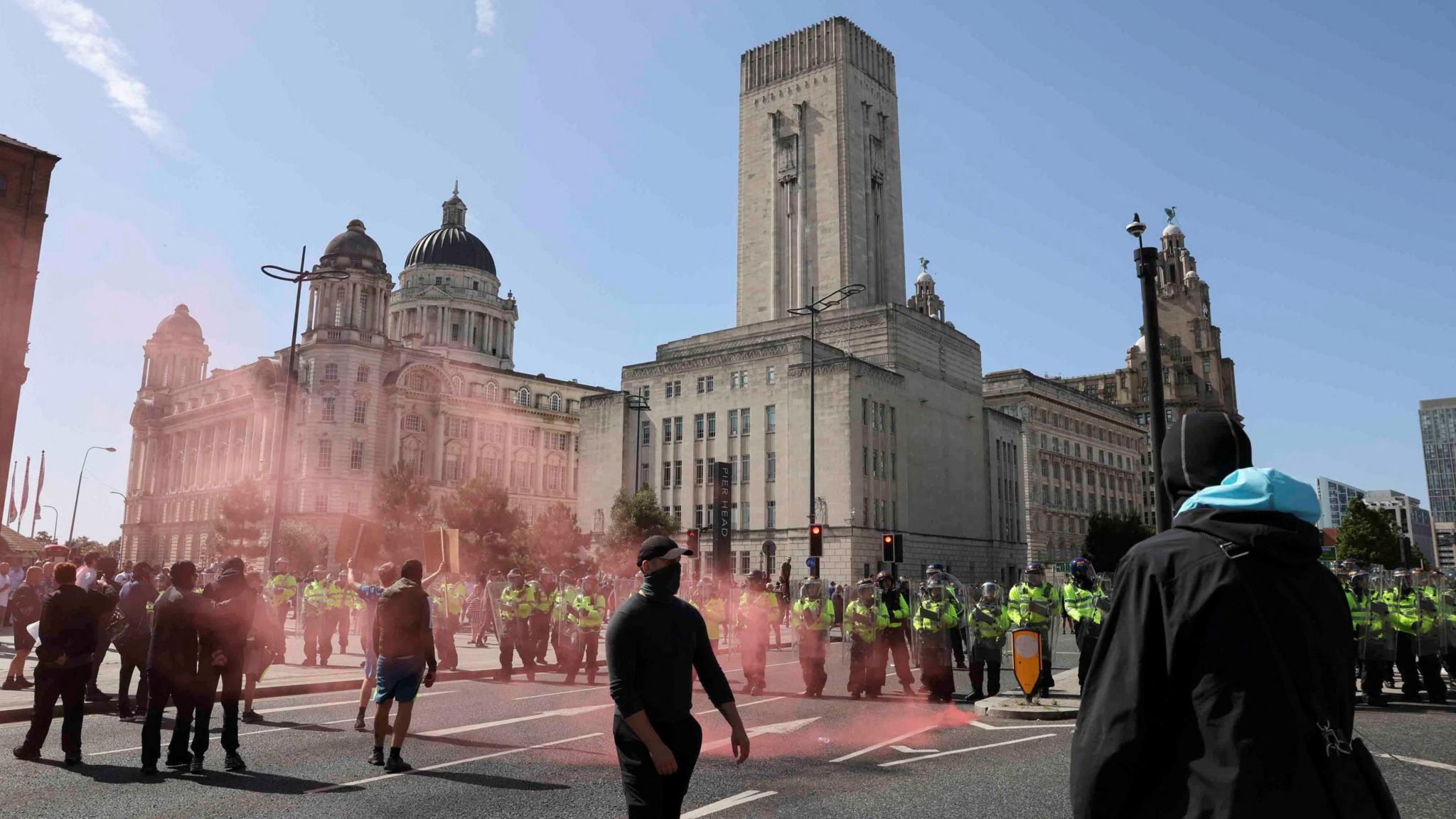 people clad in black and police officers on the Pier Head