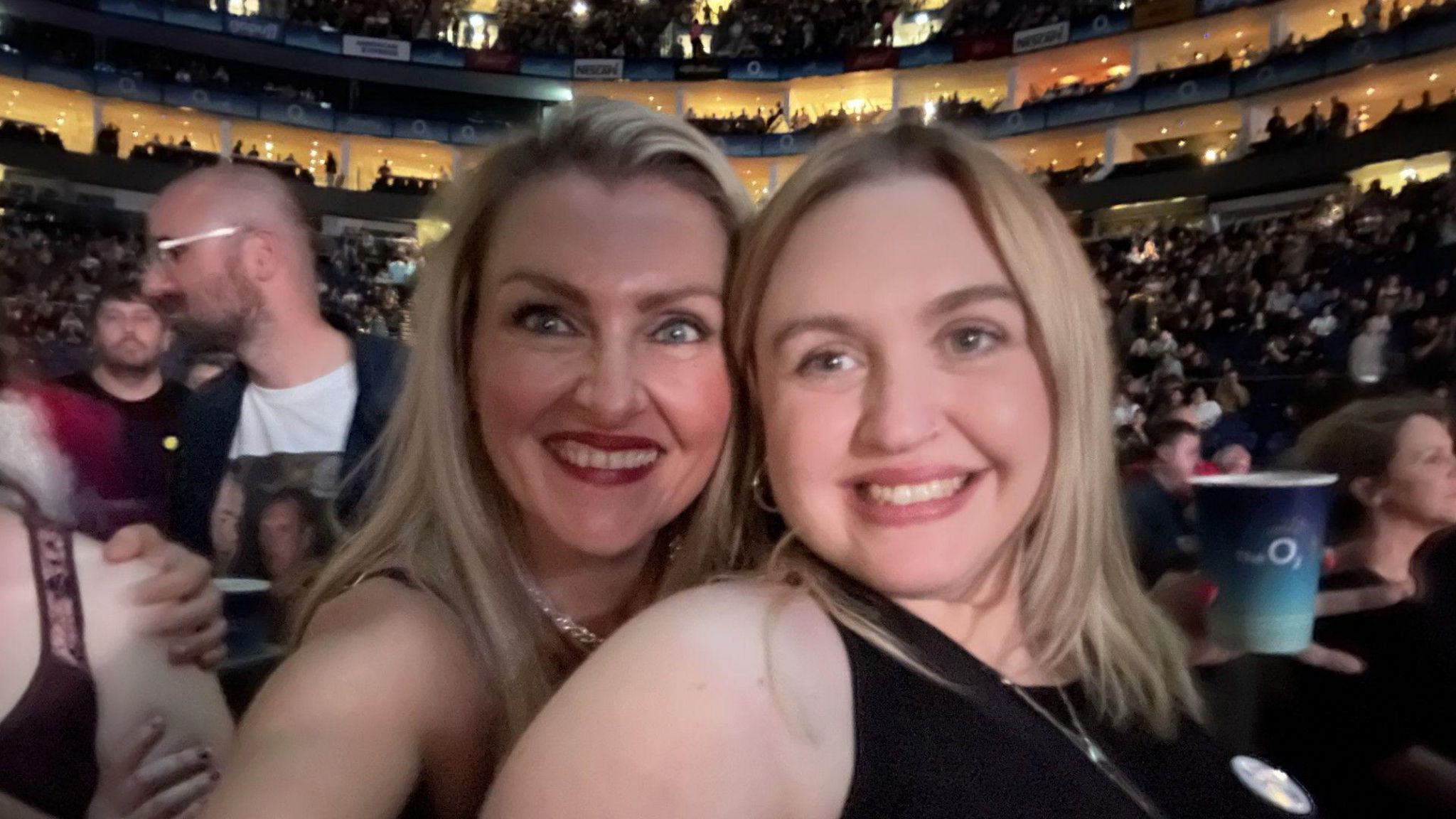 Katherine French and her friend Ashley Edwards  at a Liam Gallagher gig with a large crowd in the background