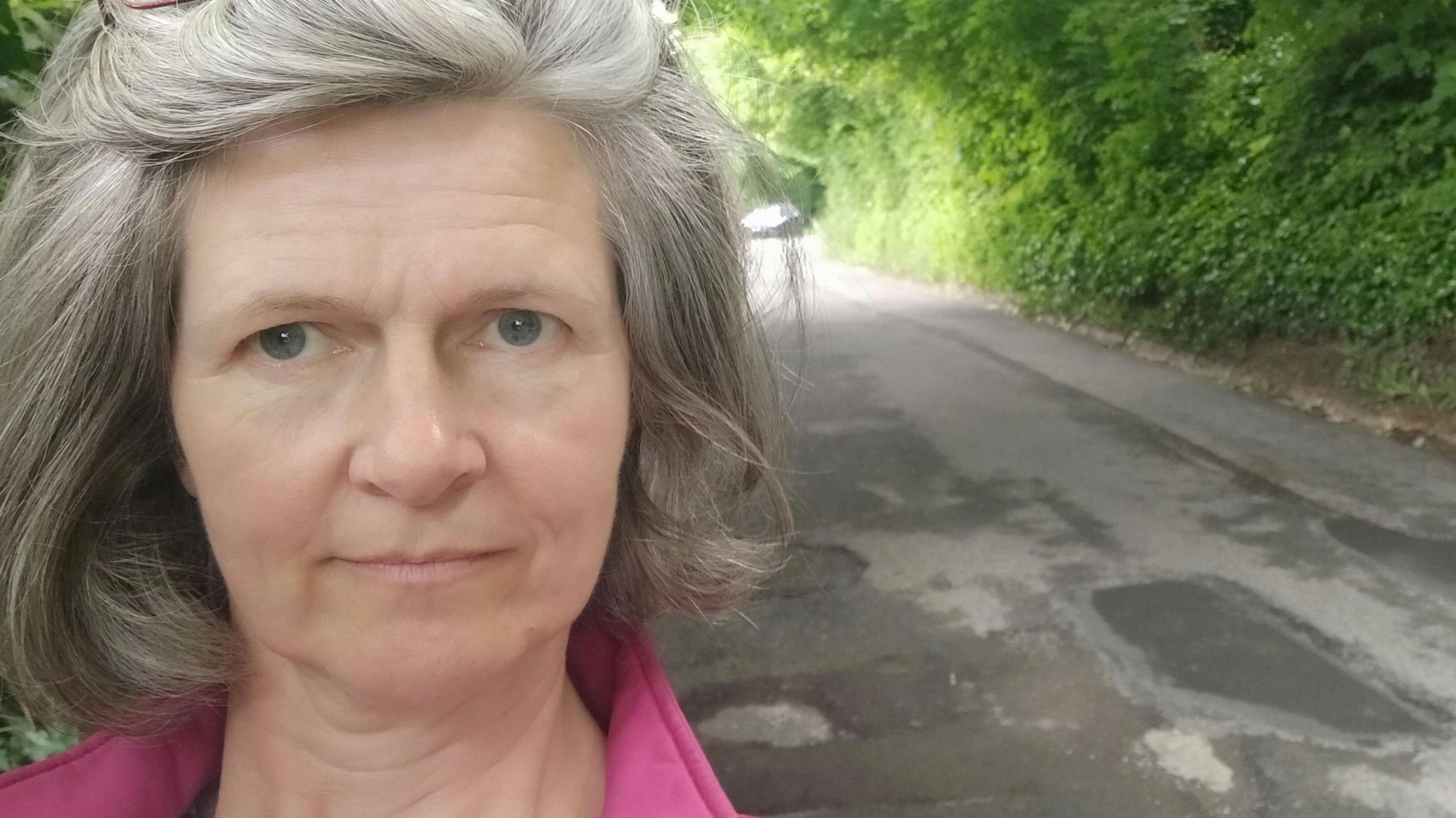 Councillor for Chalford Tricia Watson stands by the potholes on Old Neighbourhood Rd