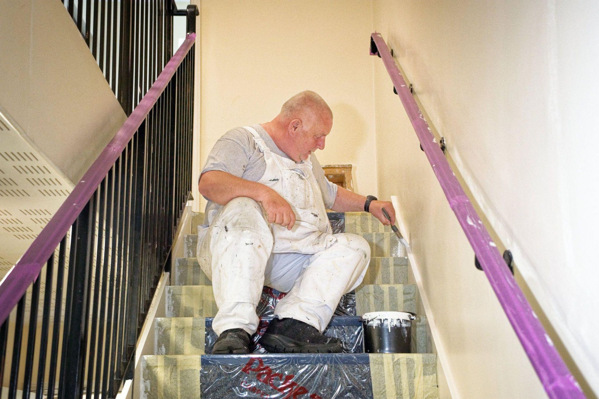Mark putting the finishing touches to a skirting board on the stairs of a flat
