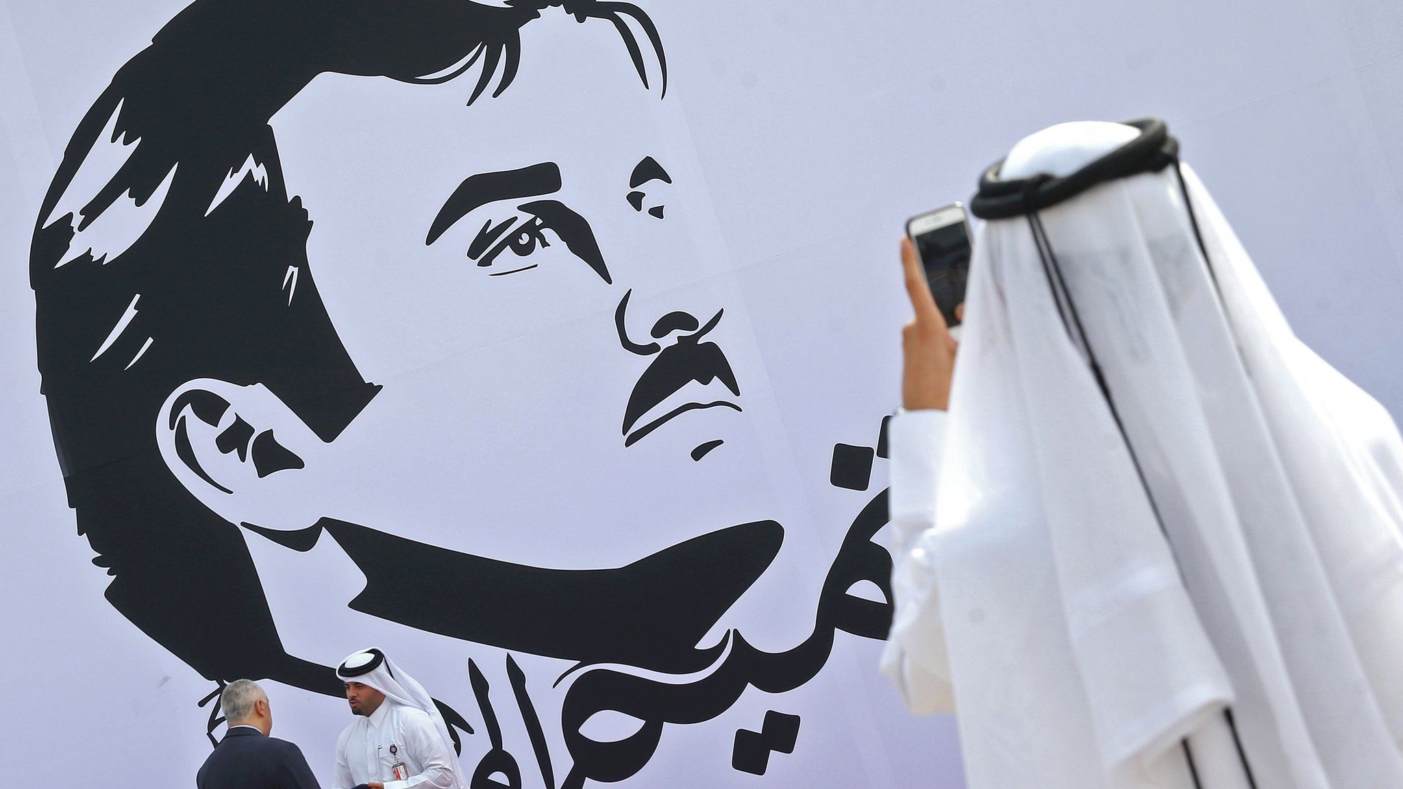 Qatari man takes a photo during the inaugural signing of a wall bearing a portrait of Qatar's Emir Sheikh Tamim bin Hamad Al Thani in Doha on 13 July 2017