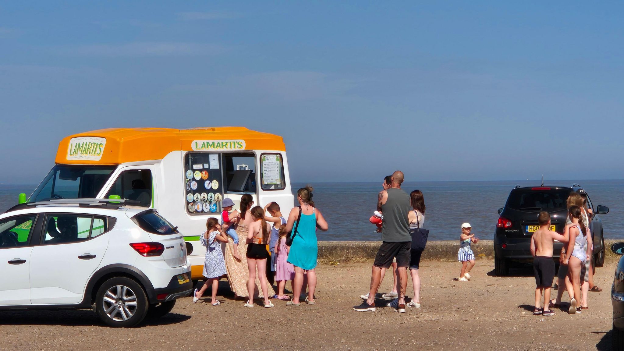 People queuing outside a white and yellow ice cream van on Lowestoft seafront