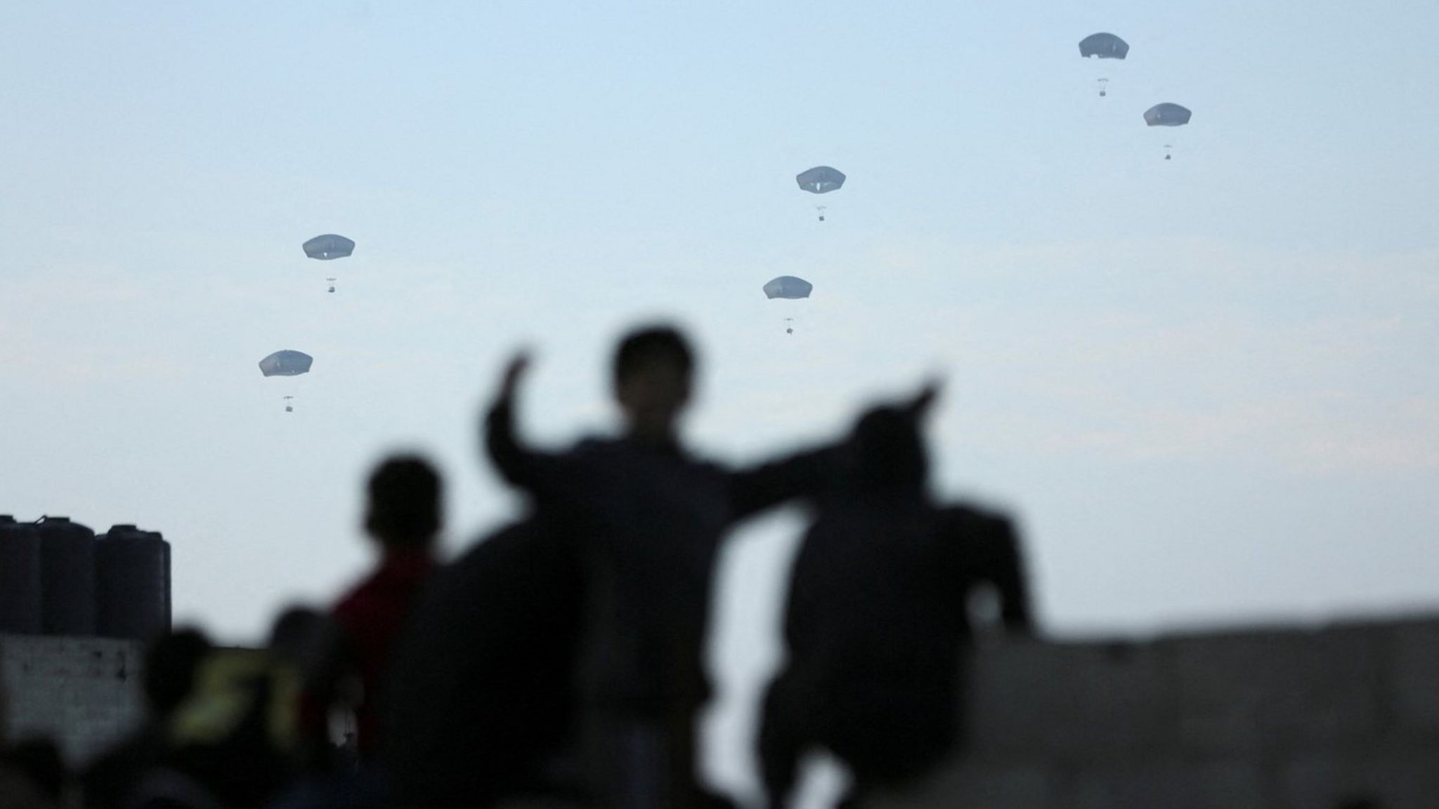 Palestinians watch as the US military airdrops aid over the Gaza Strip (2 March 2024)