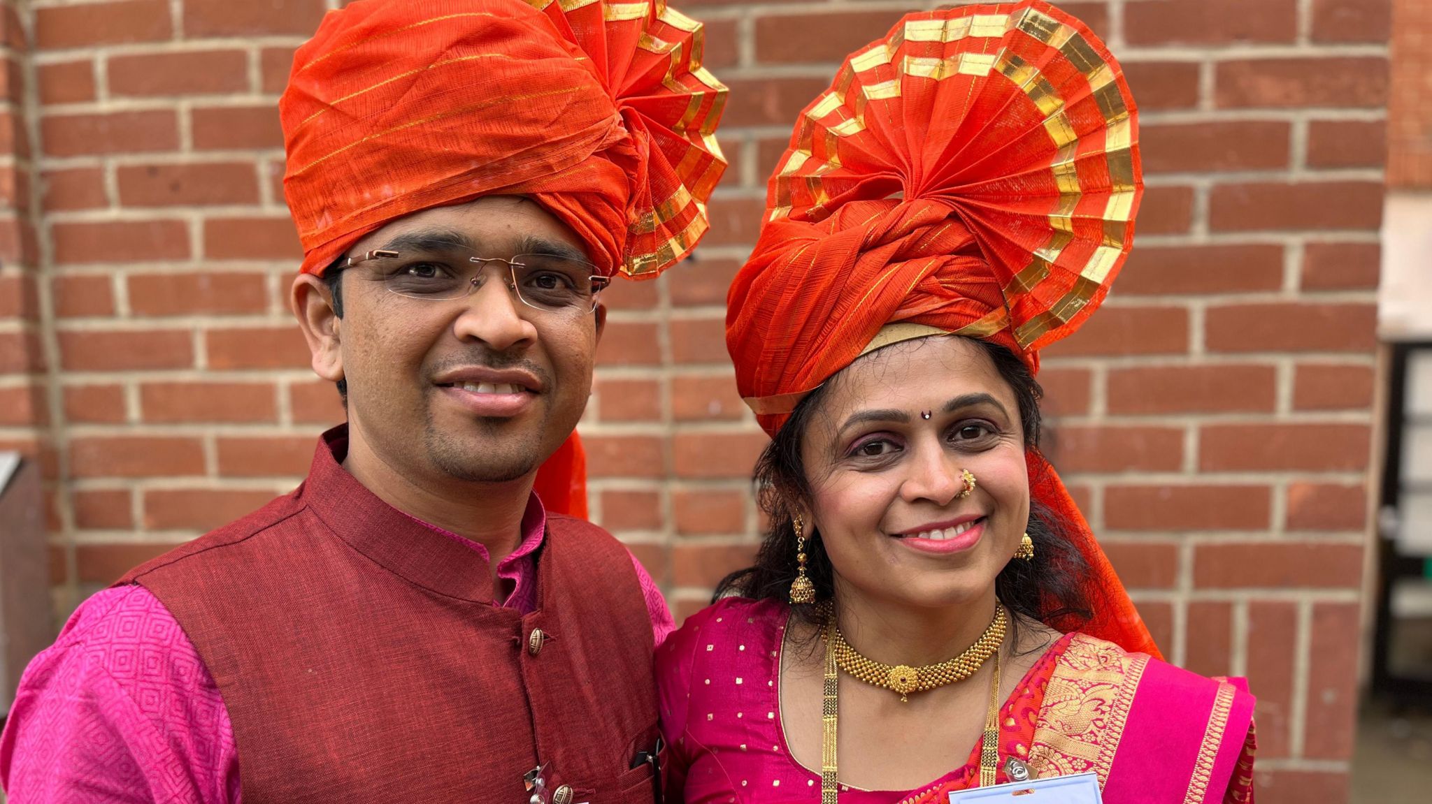 Yogesh and Snehal Ugale, a coupe of Indian heritage, wear orange headdresses
