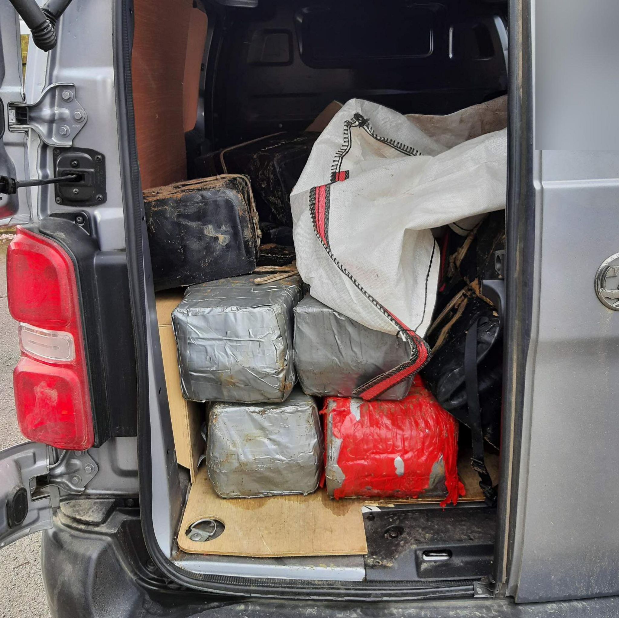 Parcels stacked up in the back of a grey van with door open