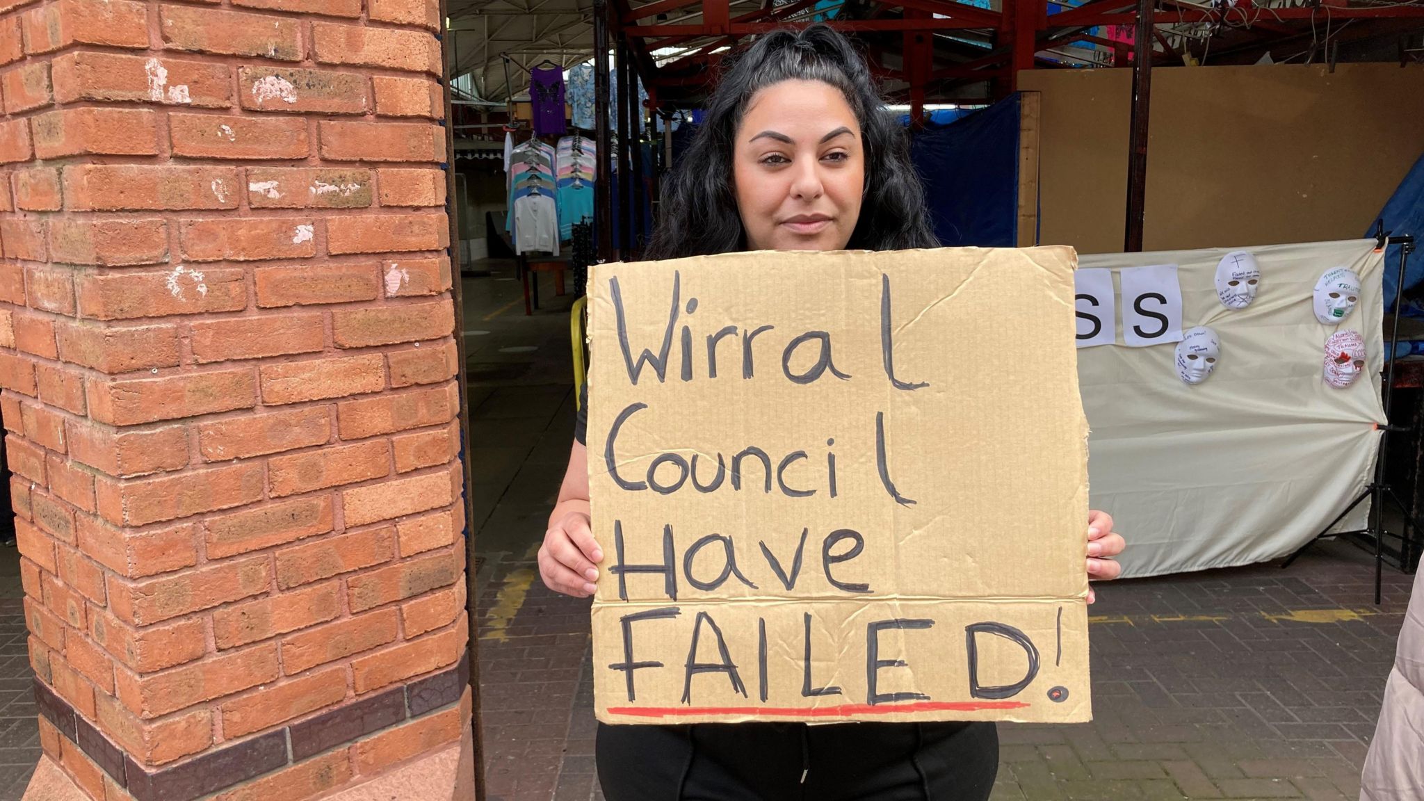 Tina Yourelis standing outside Birkenhead Market with a sign saying Wirral Council have failed