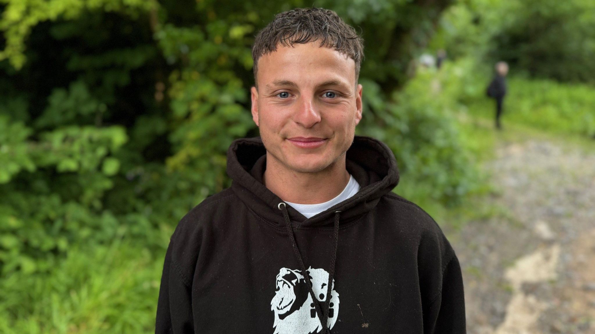 A man with a black hooded top smiling at the camera