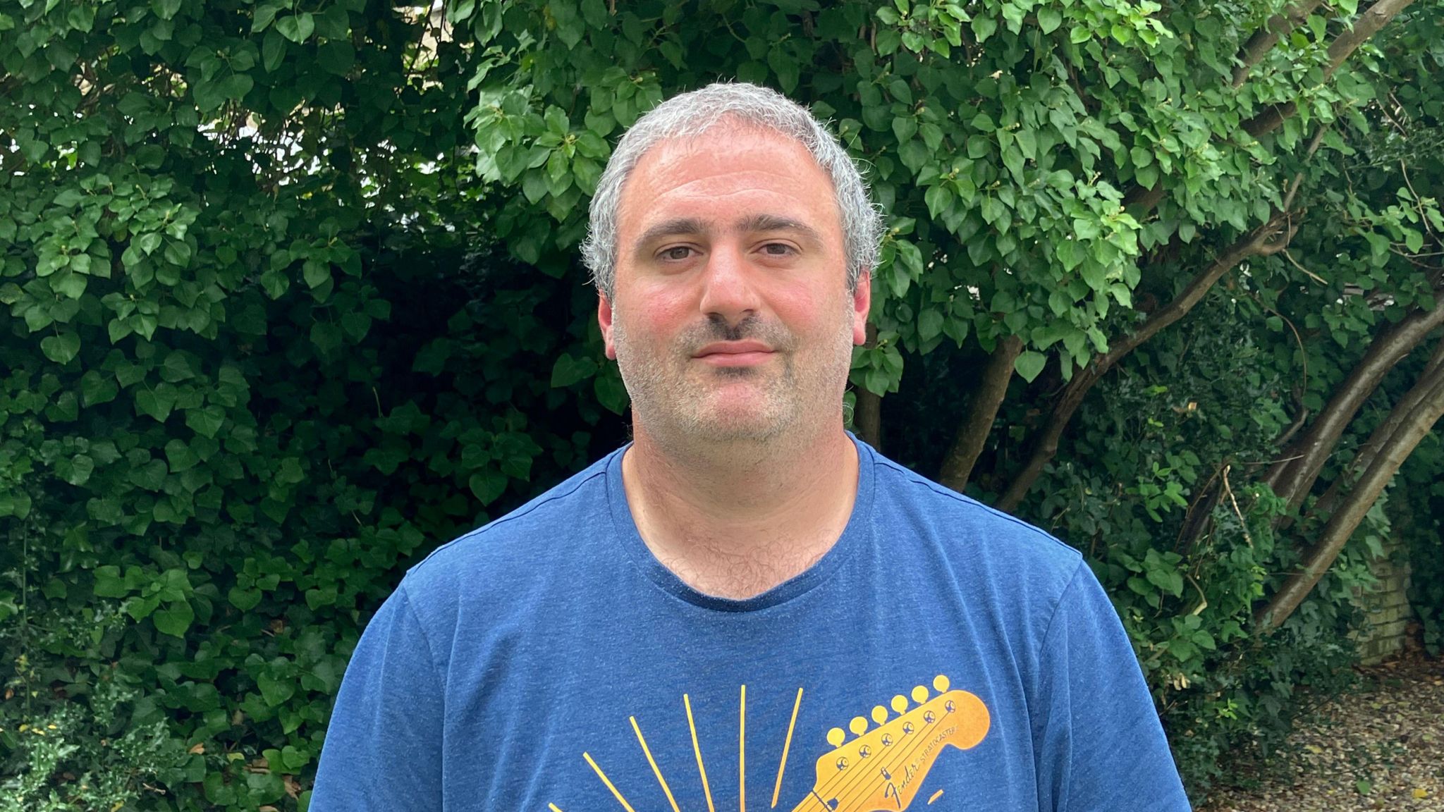 Head and shoulders picture of Simon Harris with a garden setting behind him