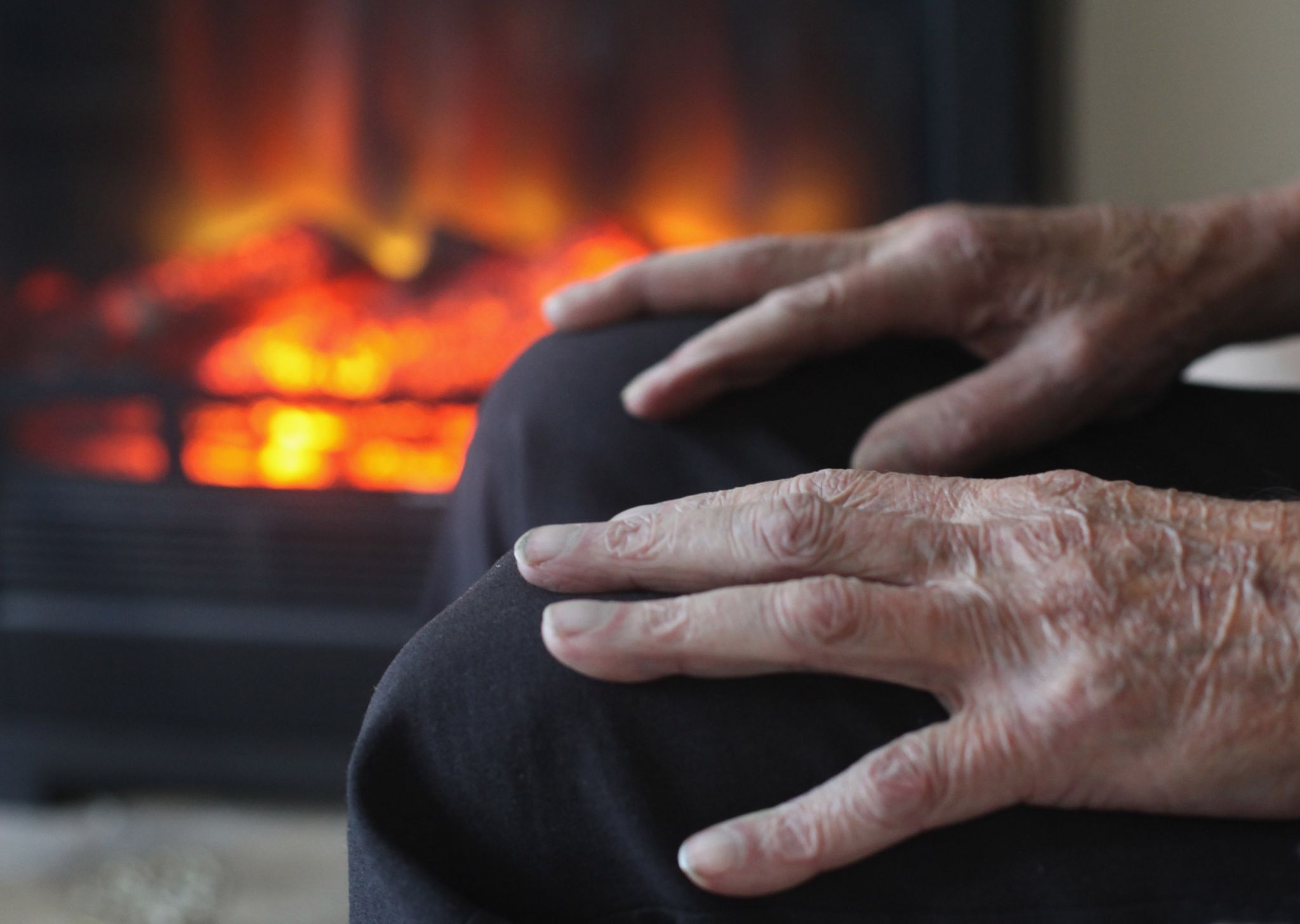 elderly person's hands, sitting by fire